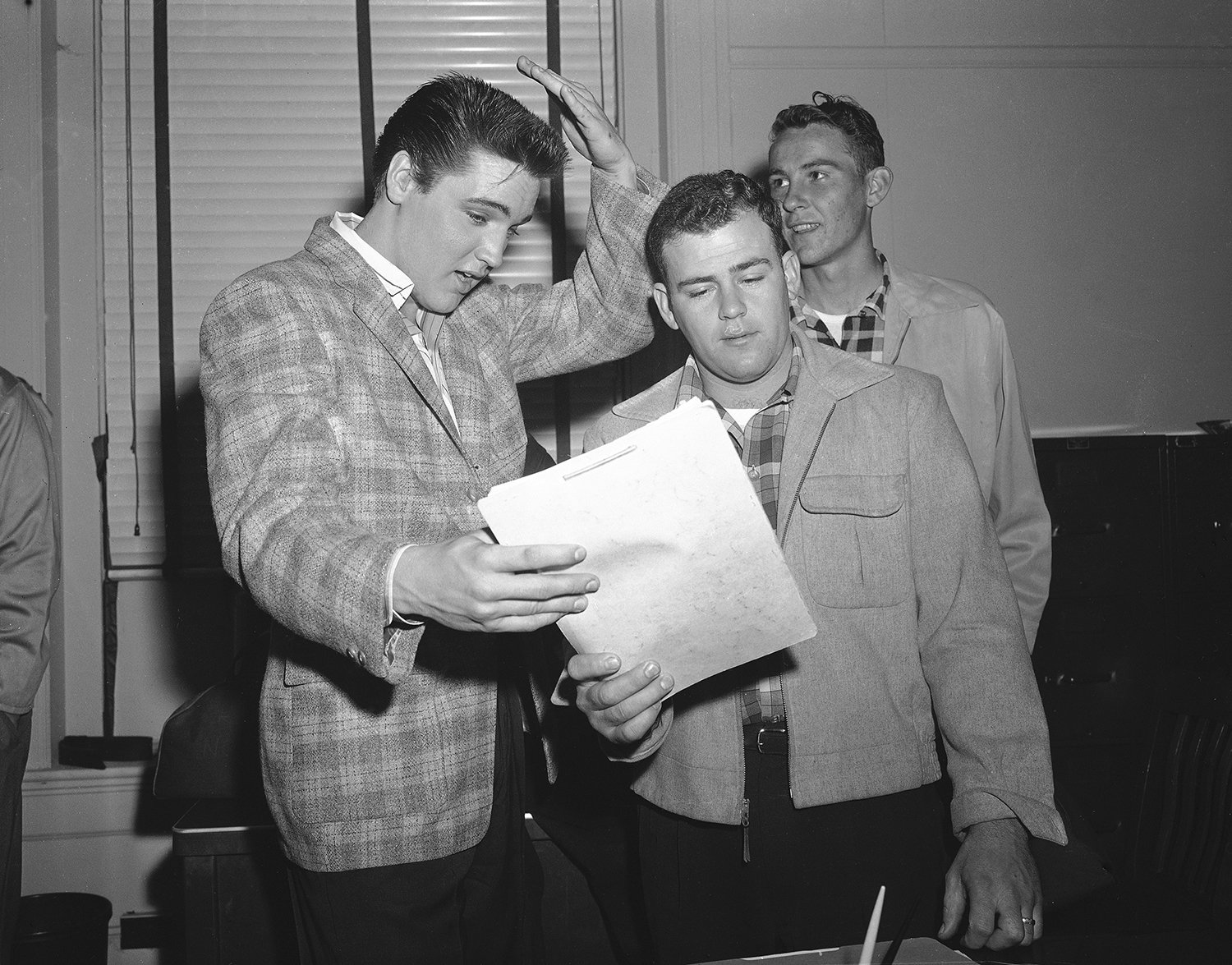  Elvis Presley, left, 23-year-old rock 'n' roll   singer, gestures at his short hair as he chats with a former school chum, Farley Gey, 22, who is entering the Army with Elvis, in Memphis, Tenn., March 24, 1958. Robert Maharrey, 22, another inductee,