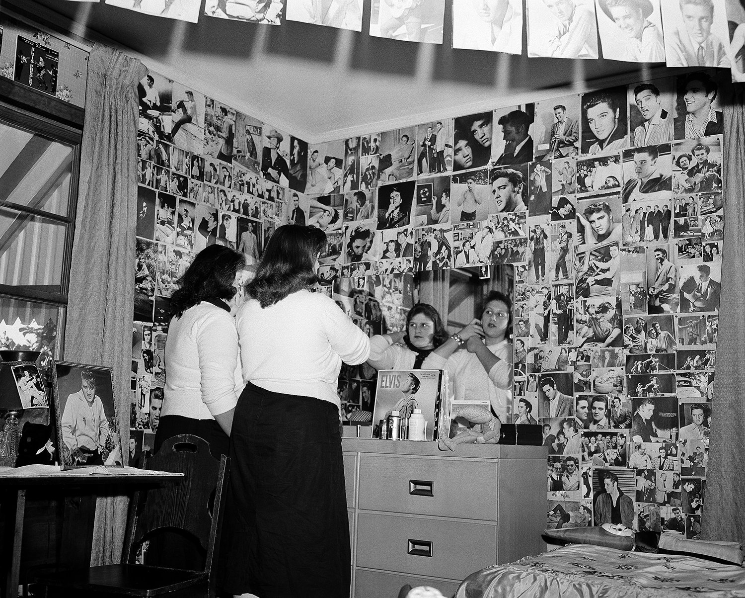  Surrounded by pictures of Elvis Presley, Oralee Davolt, 15, left, and her sister Sharyn, 14, primp at the mirror in their bedroom in Memphis, Tenn., on April 15, 1957. The girls have collected 1,087 pictures of Elvis, as well as Elvis neckties, hats