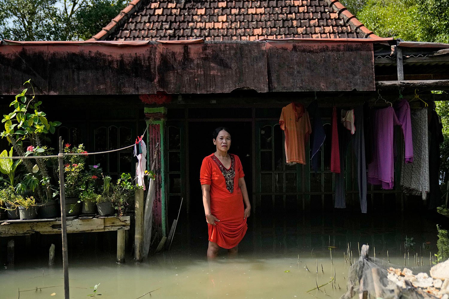  Zuriah stands outside her flooded home in Mondoliko, Central Java, Indonesia, Monday, Aug. 1, 2022.  (AP Photo/Dita Alangkara) 