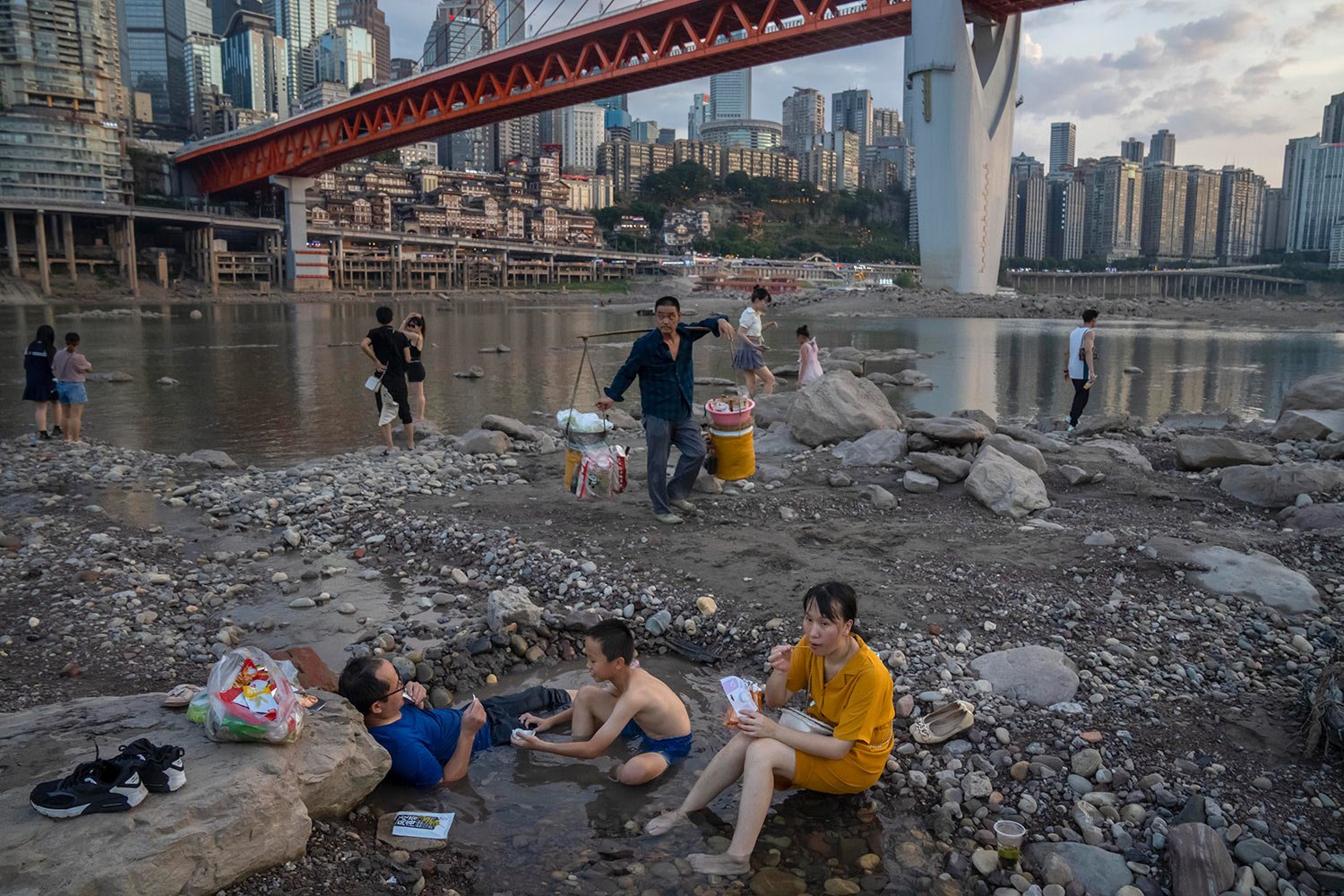  People sit in a shallow pool of water in the riverbed of the Jialing River, a tributary of the Yangtze, in southwestern China's Chongqing Municipality, Saturday, Aug. 20, 2022.  (AP Photo/Mark Schiefelbein) 