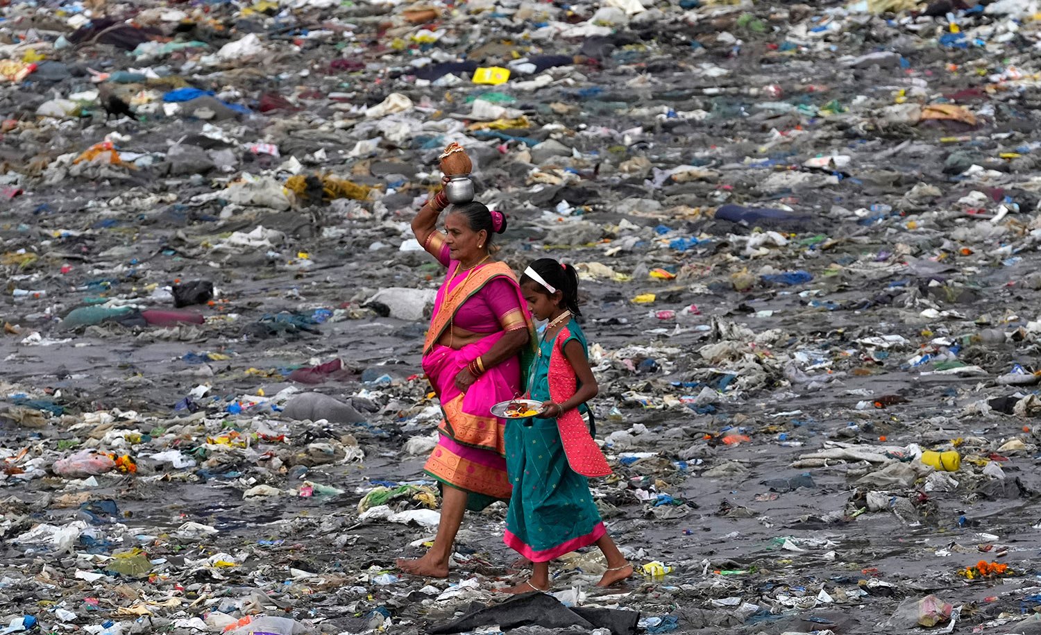  Members of the fishing community make their way through plastic waste on the beach to offer coconut to the sea on the occasion of Narli Pournima, or coconut festival in Mumbai, India, Thursday, Aug. 11, 2022. (AP Photo/Rajanish kakade) 