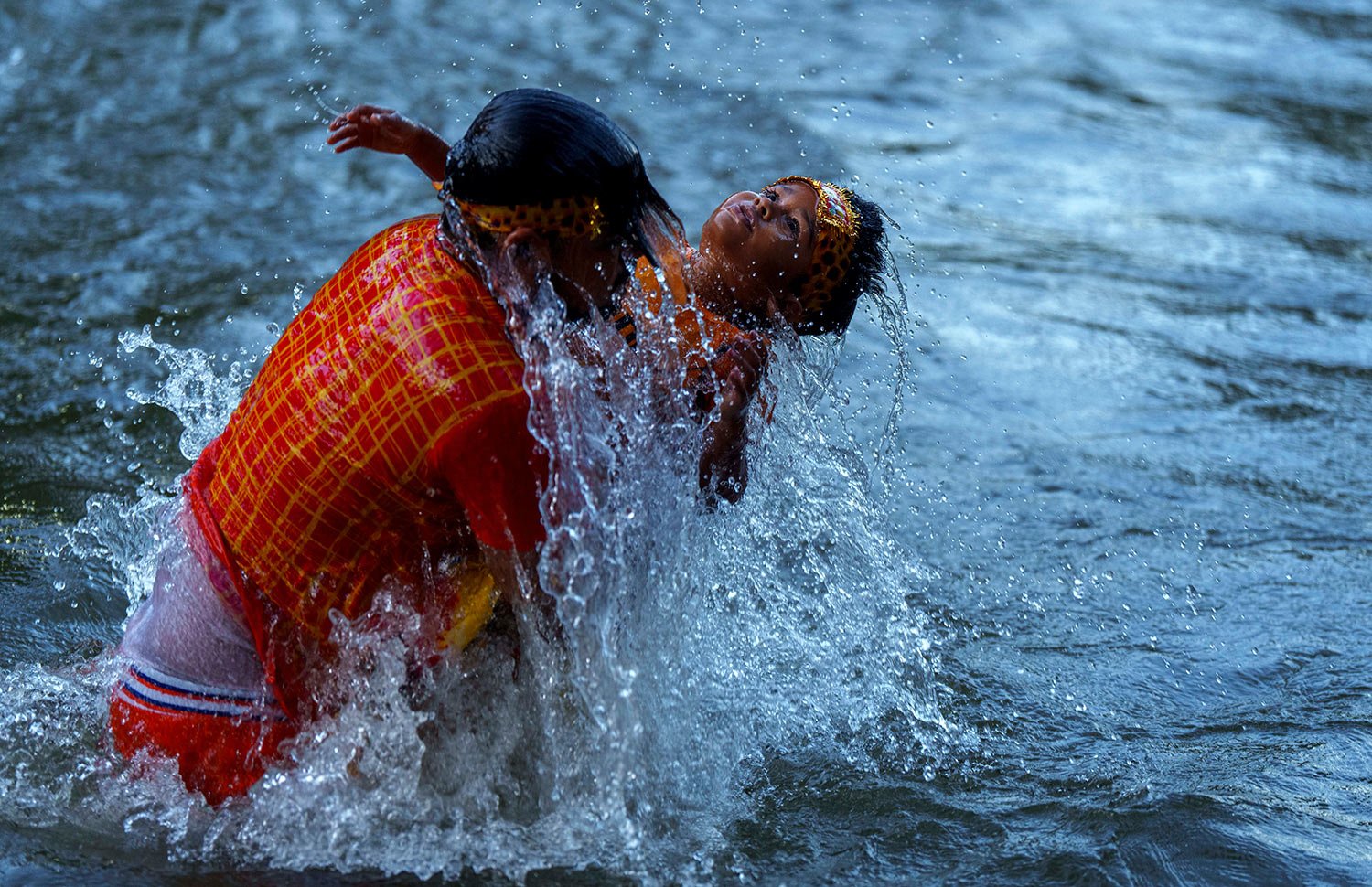  A Hindu devotee takes a holy dip with his child before collecting water from the Bagmati river during  the Bol Bom pilgrimage at Sudarijaal, on the outskirts of Kathmandu, Nepal, Monday, Aug. 8, 2022.  (AP Photo/Niranjan Shrestha) 