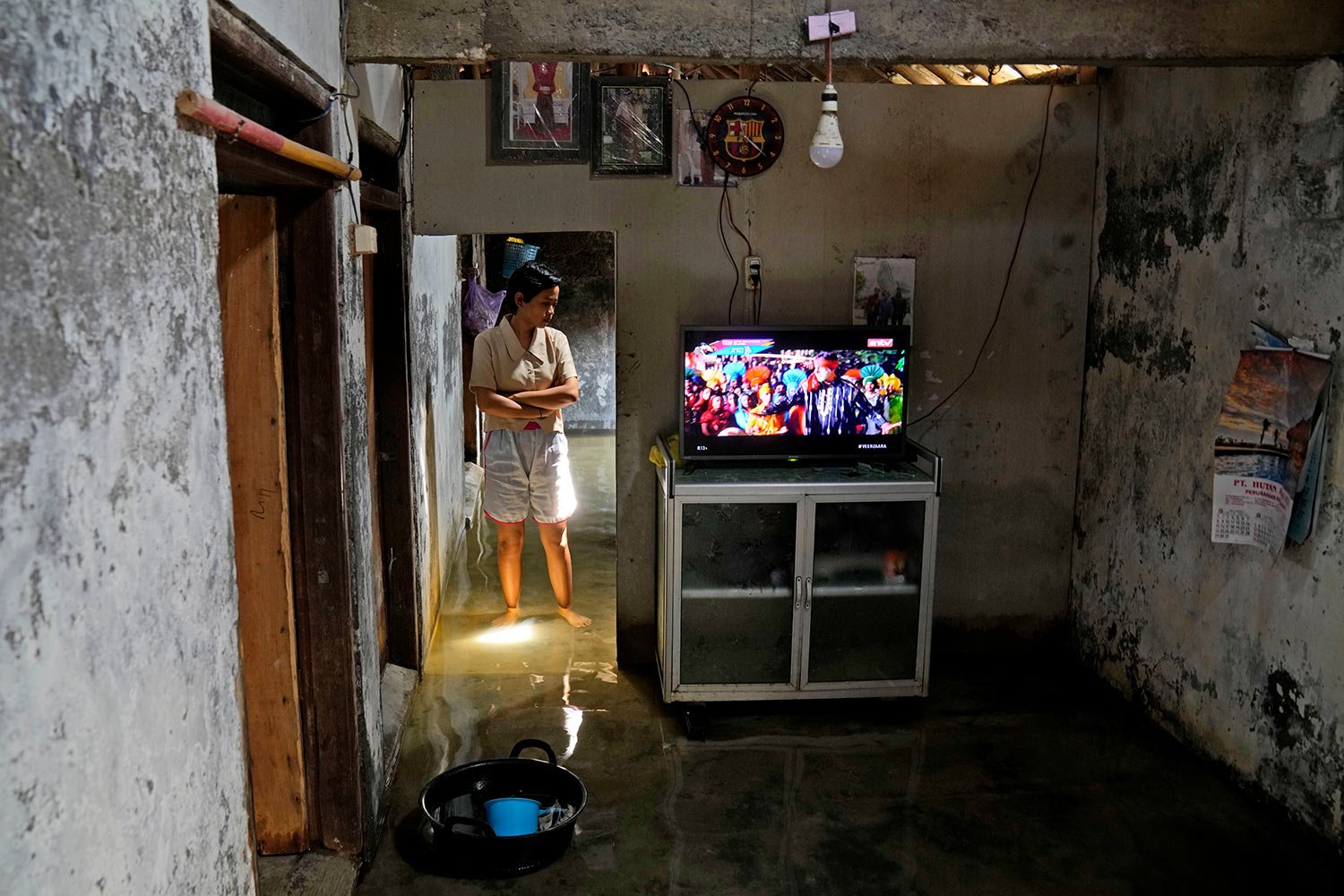  Dwi Ulfani stands inside her flooded home in Timbulsloko, Central Java, Indonesia, Saturday, July 30, 2022.   (AP Photo/Dita Alangkara) 