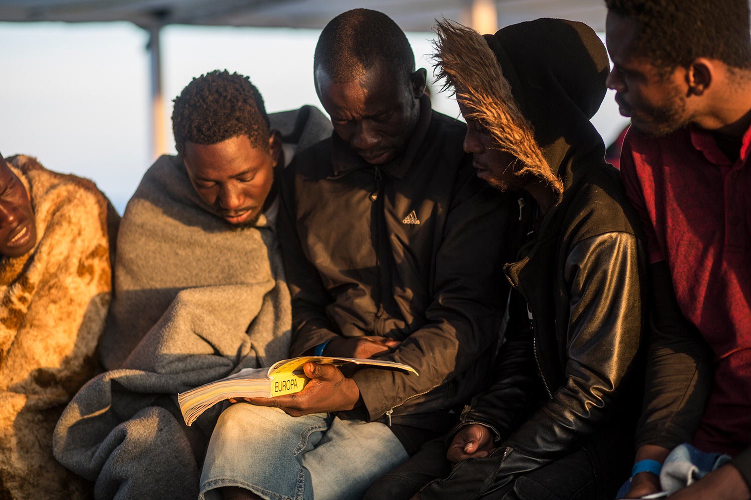  Migrants read a book about Europe on the deck of the Open Arms vessel after been rescued by the Spanish NGO Pro Activa Open Arms, about 40 miles (64 kms) from the Spanish coasts, Oct. 11, 2018. (AP Photo/Javier Fergo) 