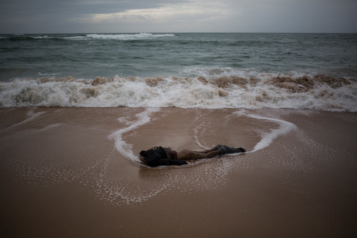  A dead body washed ashore by sea can be seen on the beach at the village of Canos de Meca where seven bodies were recovered from the sea after their precarious vessel impacted rocks while trying to reach Spanish coasts, Nov. 8, 2018. (AP Photo/Javie