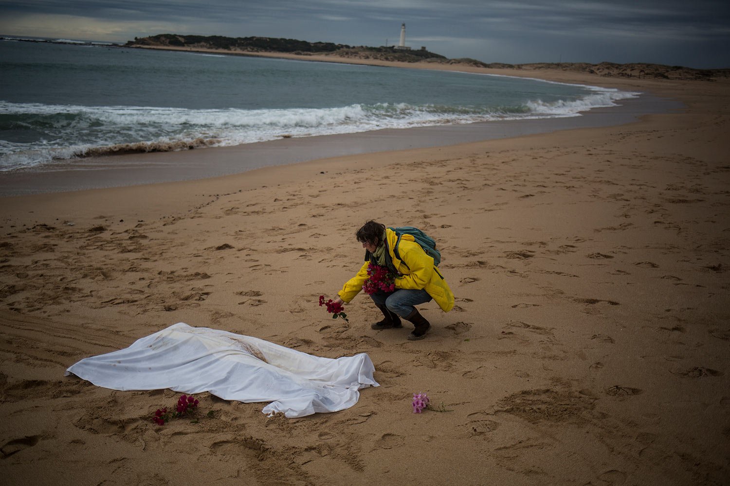  Kate Abrahams, originally from Belgium, places flowers next to the body of a dead migrant on the beach at the village of Canos de Meca, where seventeen bodies were recovered from the sea after their precarious vessel impacted rocks while trying to r