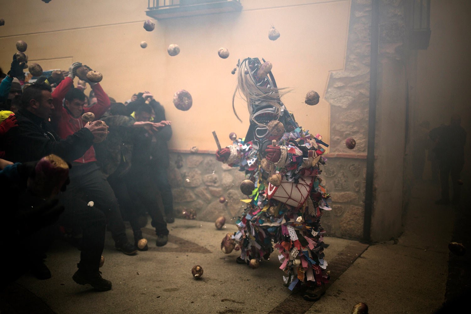  In this Jan. 19, 2019 photo, people throw turnips at the Jarramplas as he makes his way through the streets beating his drum during the Jarramplas festival in the tiny southwestern Spanish town of Piornal, Spain. The Jarramplas festival centres arou