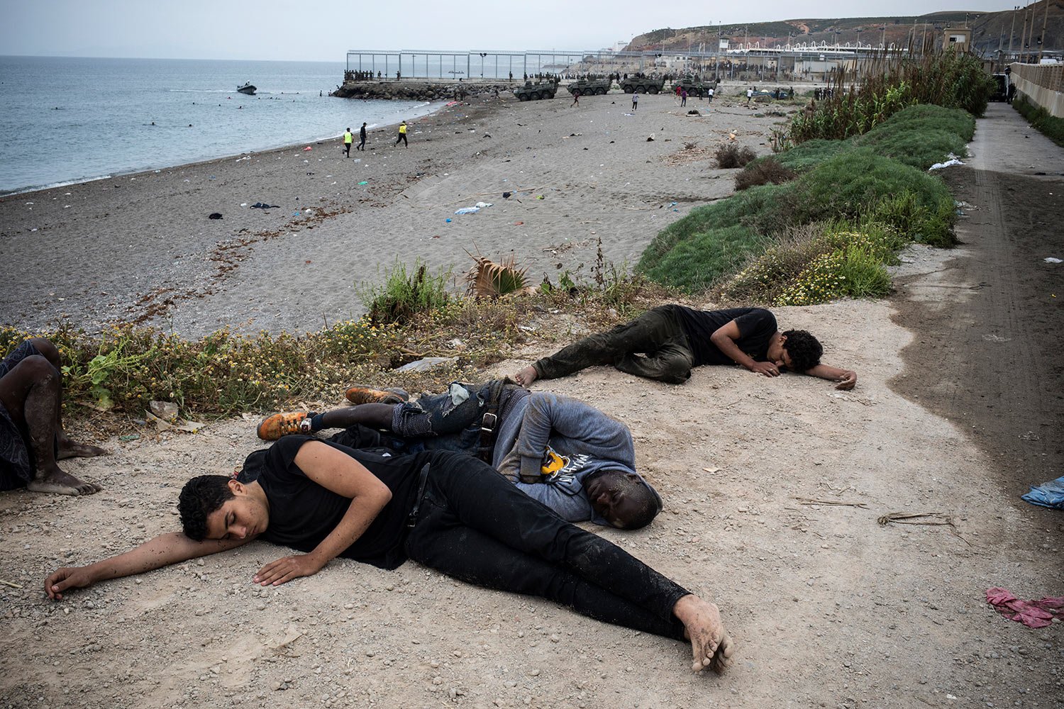  Men lie on the ground after arriving in the Spanish territory at the border of Morocco and Spain, at the Spanish enclave of Ceuta, May 18, 2021. (AP Photo/Javier Fergo) 