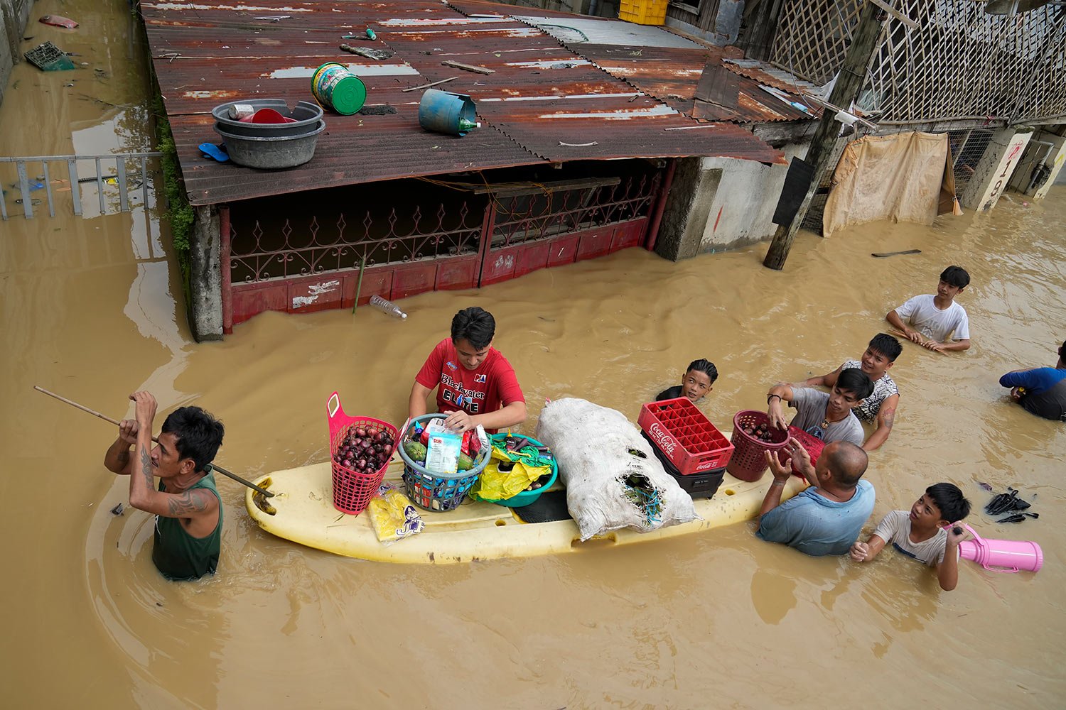  Residents give away onions and other foods along a flooded road due to Typhoon Noru in San Miguel town, Bulacan province, Philippines, Monday, Sept. 26, 2022. (AP Photo/Aaron Favila) 