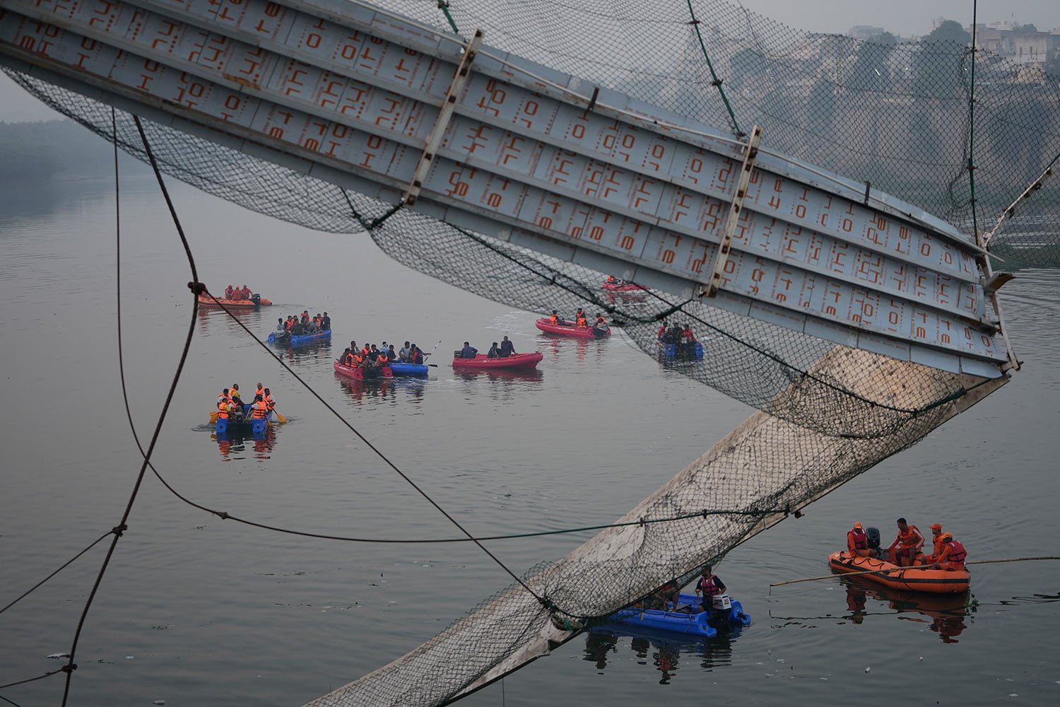  Rescuers on boats search in the Machchu river next to a cable suspension bridge that collapsed in Morbi town of western state Gujarat, India, Monday, Oct. 31, 2022. (AP Photo/Ajit Solanki) 