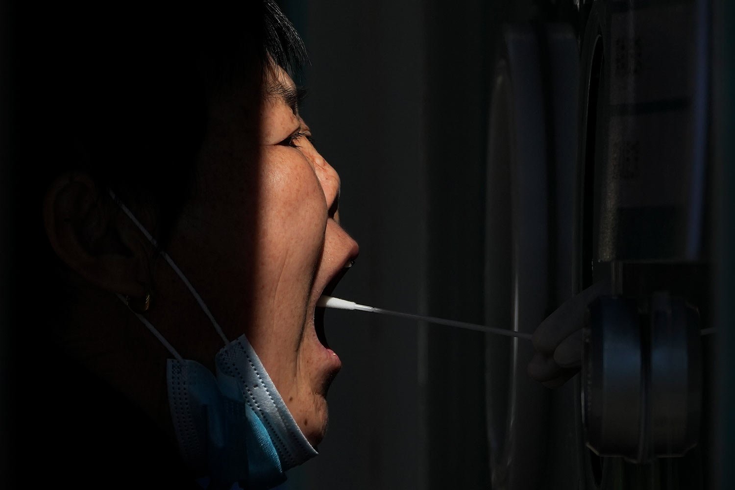  A woman gets her routine COVID-19 throat swab at a coronavirus testing site in Beijing, Sunday, Oct. 9, 2022. (AP Photo/Andy Wong) 