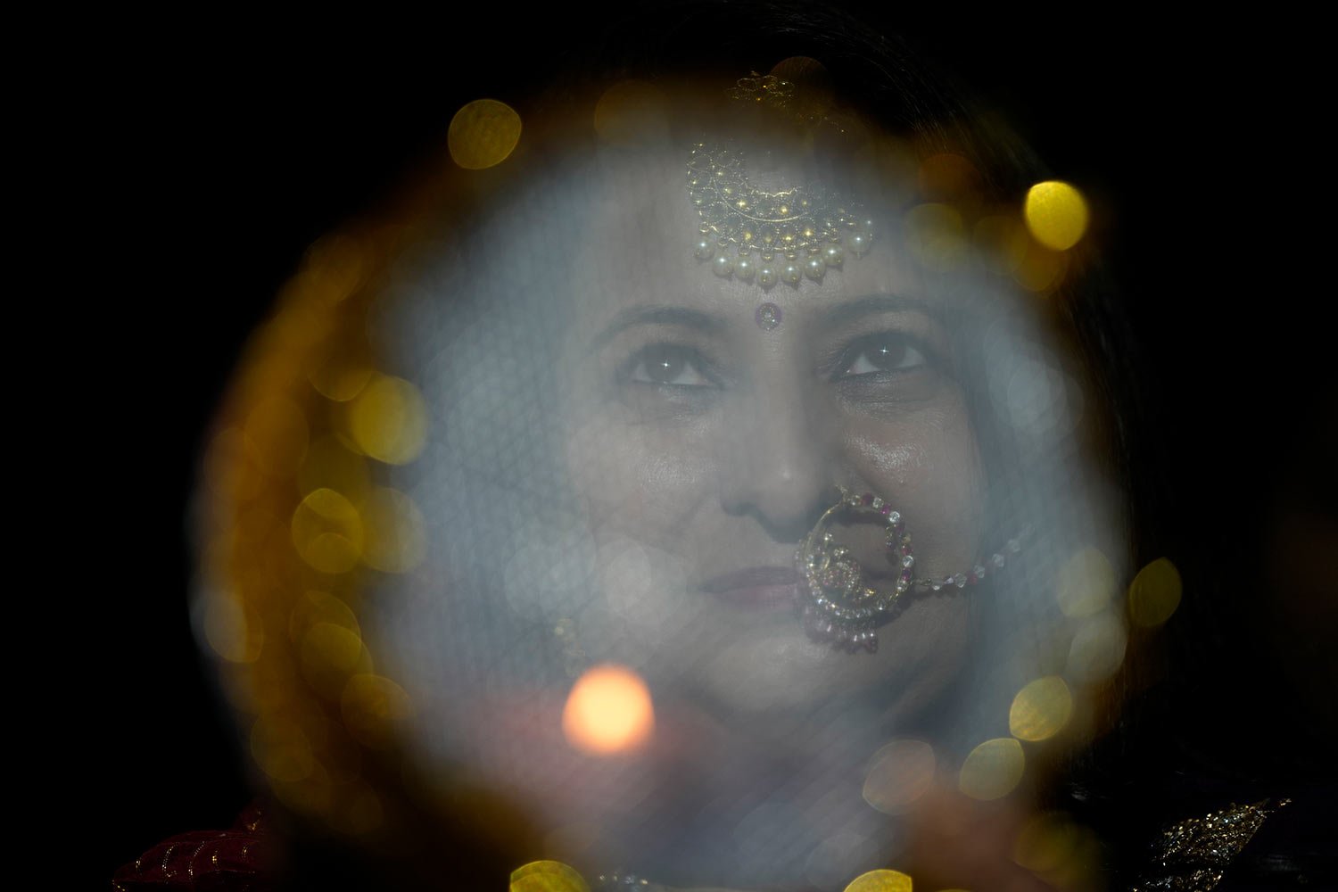  A married Hindu woman looks at the moon through a sieve as part of a ritual to break her fast during Karva Chauth festival in Jammu, India, Thursday, Oct. 13, 2022. (AP Photo/Channi Anand) 