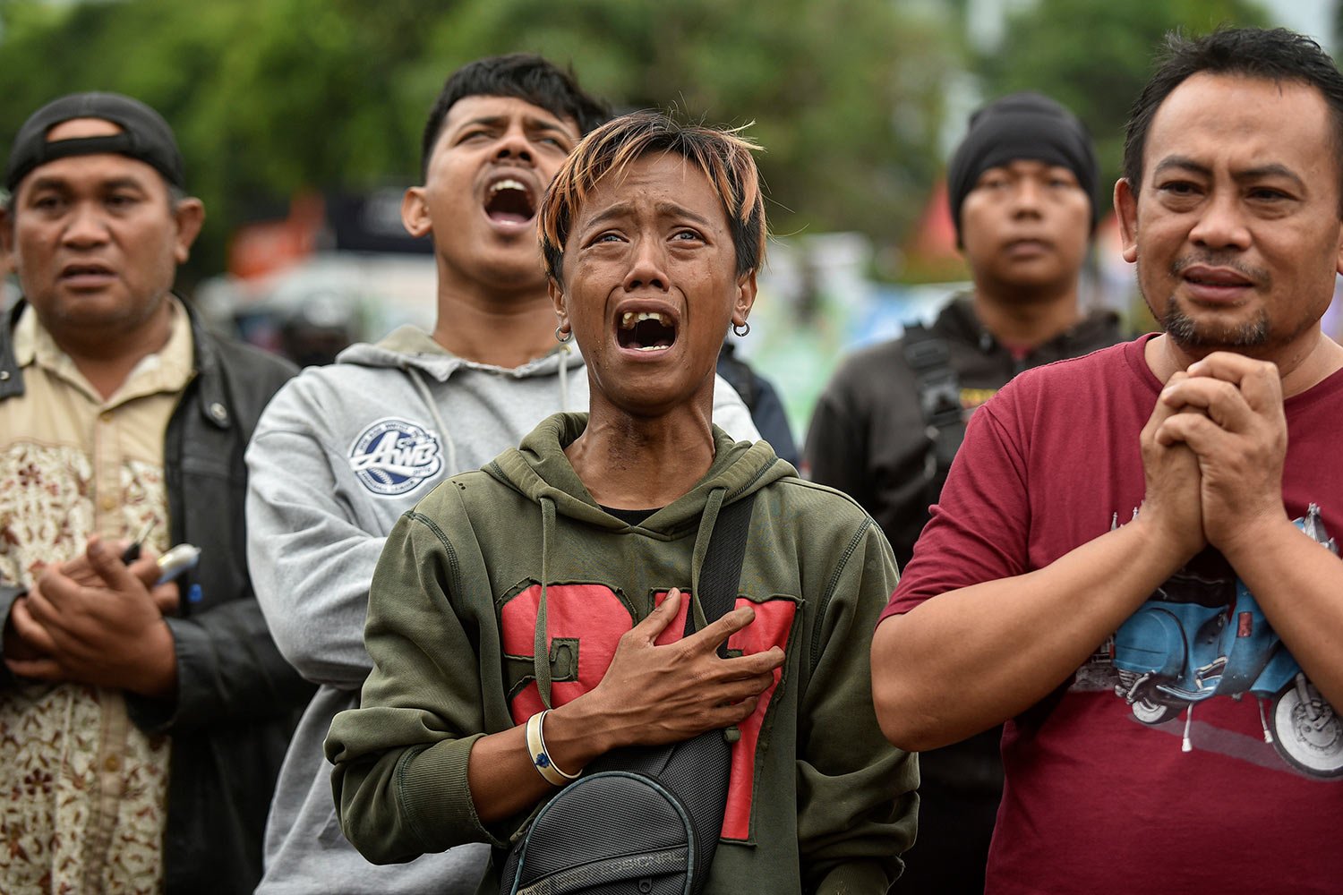  Men are overcome by emotion as they offer prayers for the victims of Saturday's soccer stampede outside the Kanjuruhan Stadium in Malang, East Java, Indonesia, Wednesday, Oct. 5, 2022. (AP Photo/Dicky Bisinglasi) 