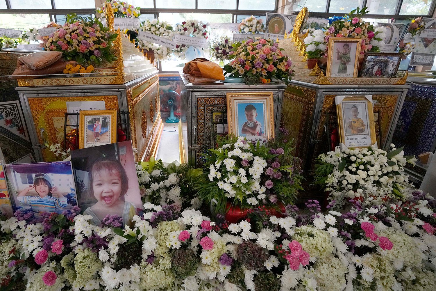  Photos of the victims of a mass killing attack are displayed around coffins inside the Wat Rat Samakee temple in the rural town of Uthai Sawan, north eastern Thailand, Sunday, Oct. 9, 2022. (AP Photo/Sakchai Lalit) 