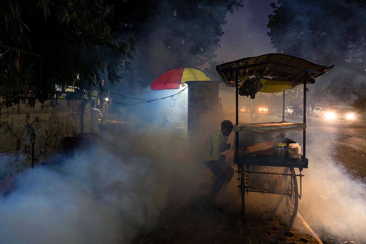  A street vendor tries to avoid fumes as a municipal worker fumigates a residential area to prevent mosquitoes from breeding in Prayagraj, in the northern state of Uttar Pradesh, India, Wednesday, Oct. 12, 2022. (AP Photo/Rajesh Kumar Singh) 