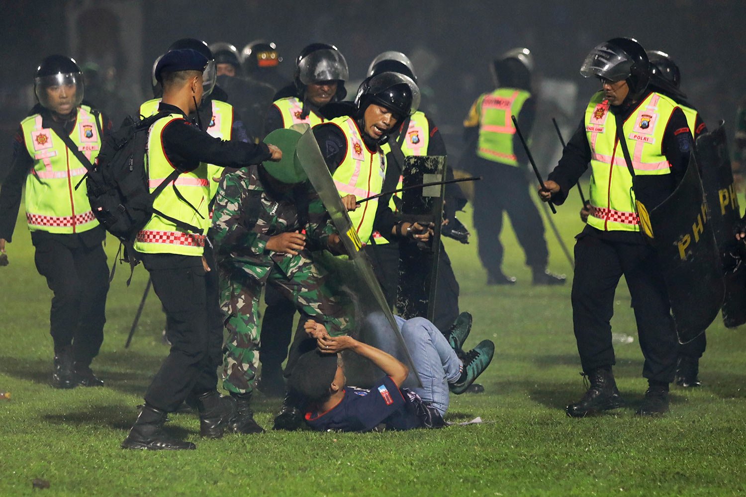  Security officers detain a fan during a clash between supporters of two Indonesian soccer teams at Kanjuruhan Stadium in Malang, East Java, Indonesia, Saturday, Oct. 1, 2022.  (AP Photo/Yudha Prabowo) 