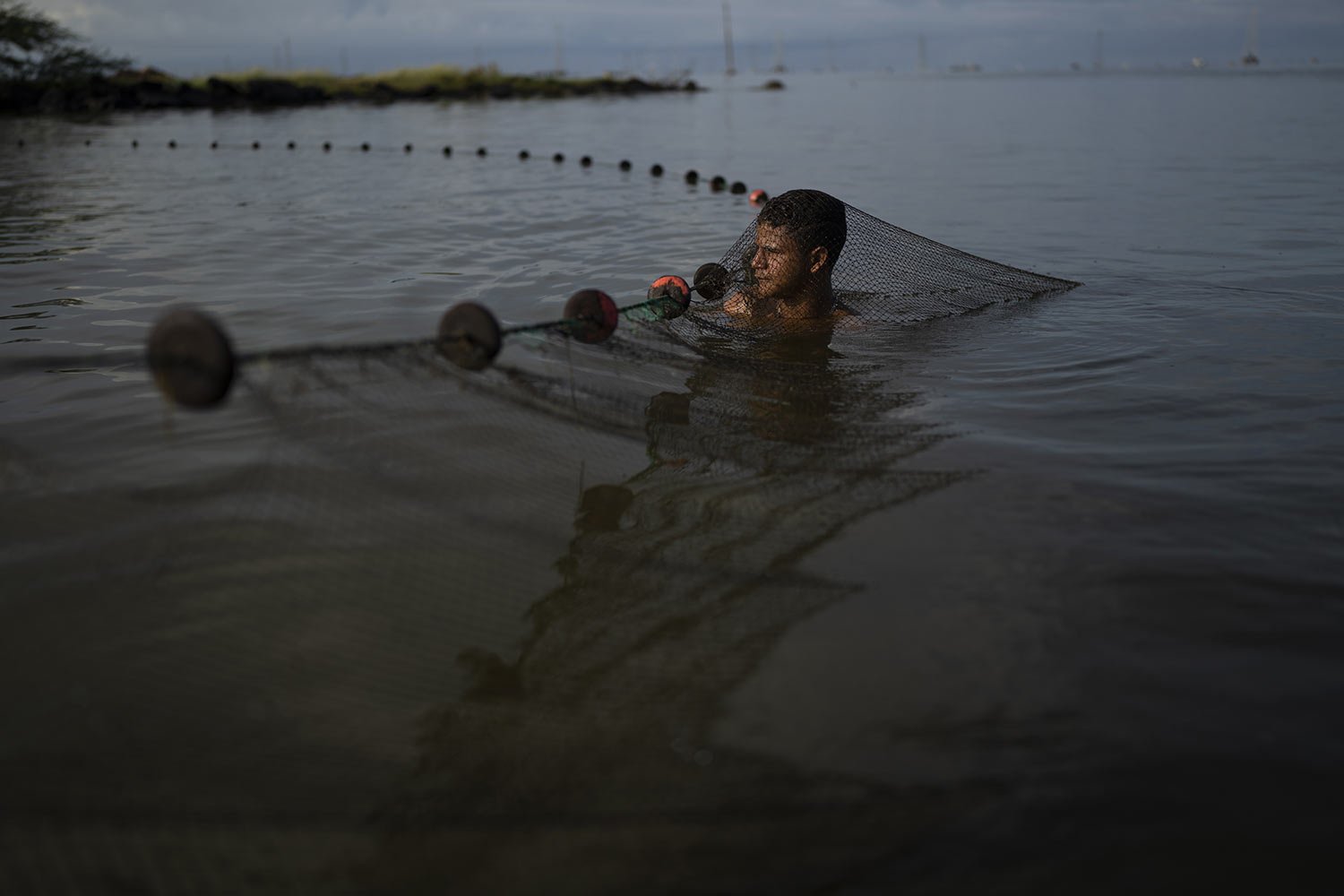  Enderson Mendoza cleans a fishing net as he and others fish for shrimp in Lake Maracaibo near Cabimas, Venezuela, Wednesday, Oct. 12, 2022. (AP Photo/Ariana Cubillos) 