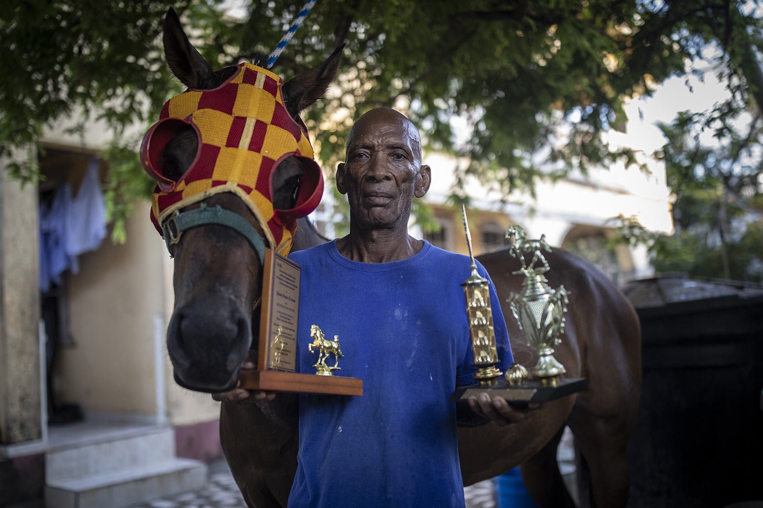  Horse trainer Denis Hooker poses with his horse Pereque and Pereque's winning trophies on San Andres Island in Colombia, Friday, Nov. 11, 2022. (AP Photo/Ivan Valencia) 