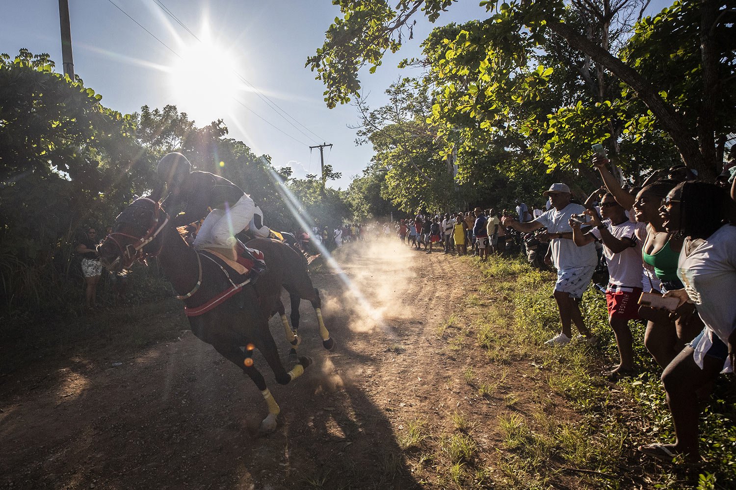  Spectators cheer as racehorse Time Will Tell runs past during a race through the forest on San Andres Island in Colombia, Saturday, Nov. 12, 2022. (AP Photo/Ivan Valencia) 