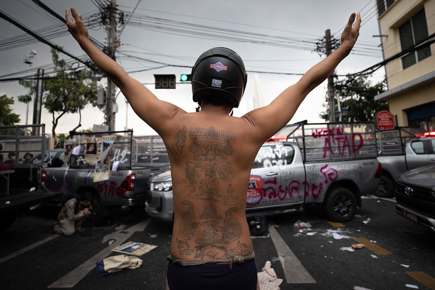  A protester raises his arms behind vandalized police vehicles during a confrontation with police as they try to march to the Asia-Pacific Economic Cooperation APEC summit venue, Friday, Nov. 18, 2022, in Bangkok, Thailand. (AP Photo/Wason Wanichakor
