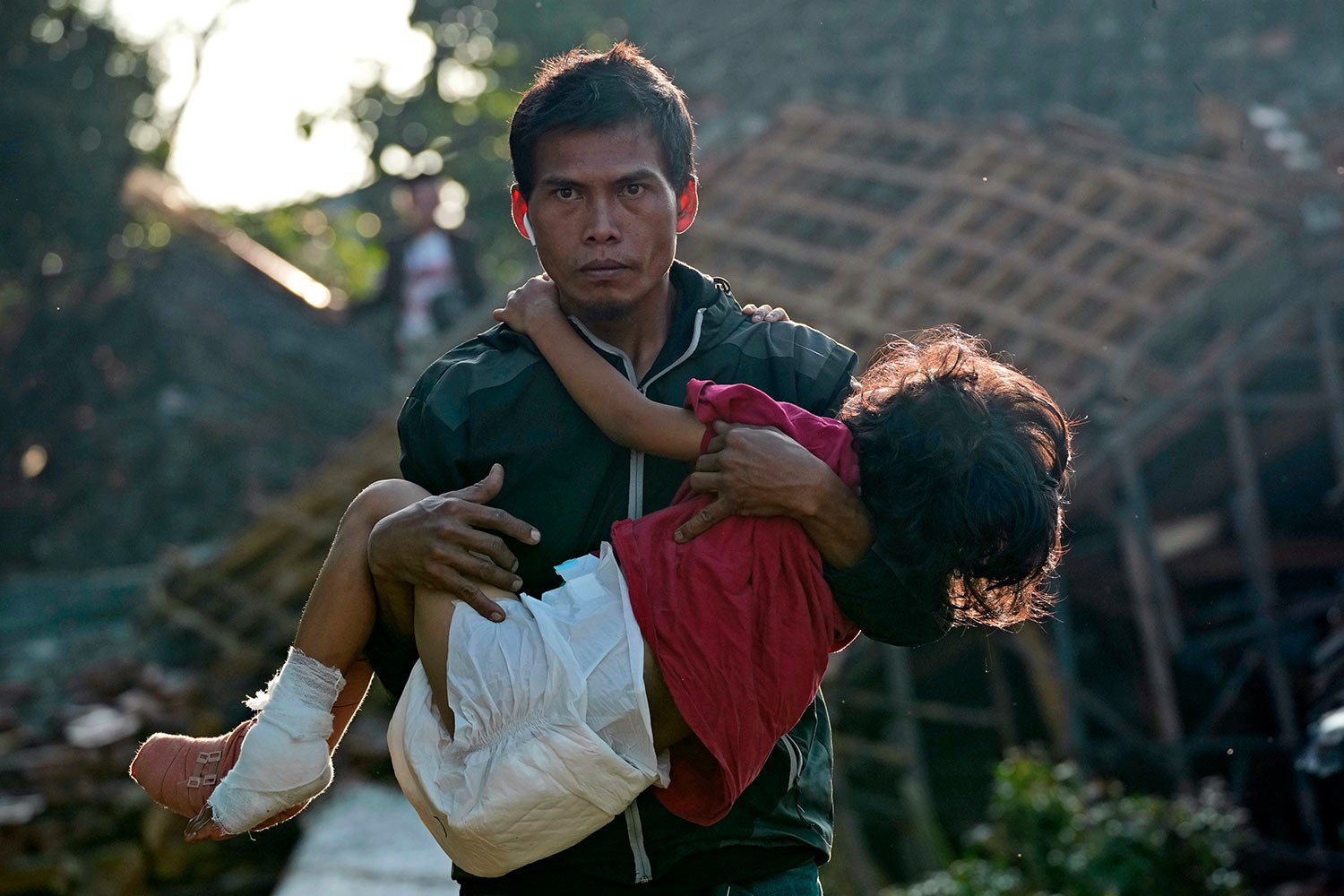  A man carries his injured daughter as they head to a temporary shelter for those displaced by Monday's earthquake in Cianjur, West Java, Indonesia, Thursday, Nov. 24, 2022. (AP Photo/Tatan Syuflana) 