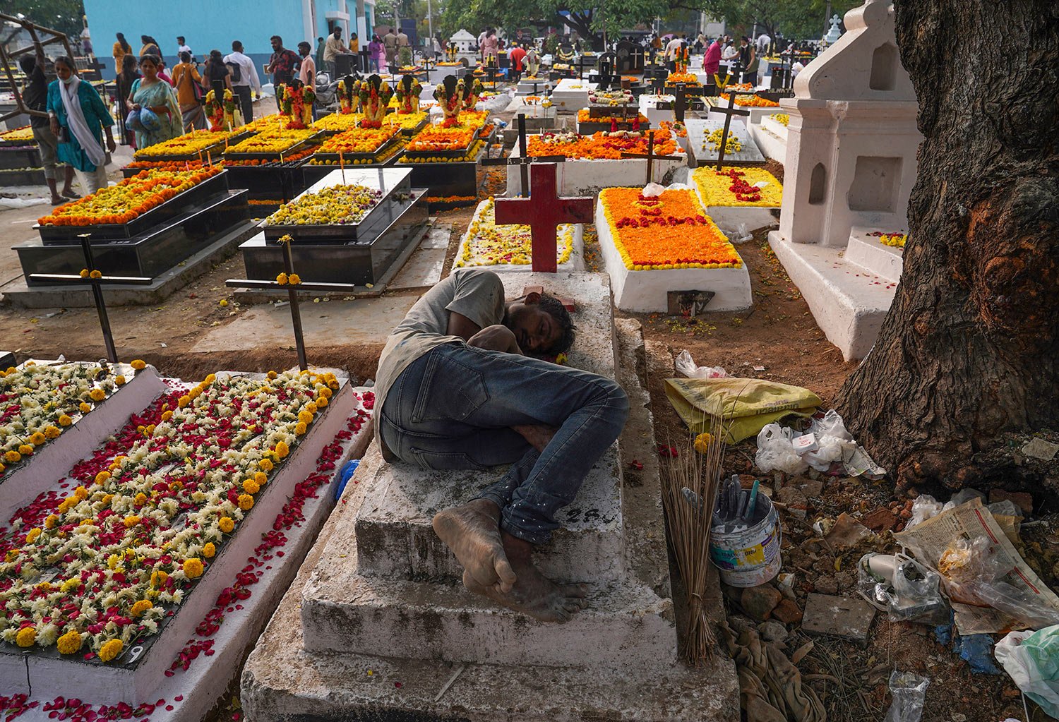  A worker rests on a grave as friends and families gather with candles and flowers to offer prayers for departed souls on All Souls' Day in Hyderabad, India, Wednesday, Nov. 2, 2022.  (AP Photo/Mahesh Kumar A.) 
