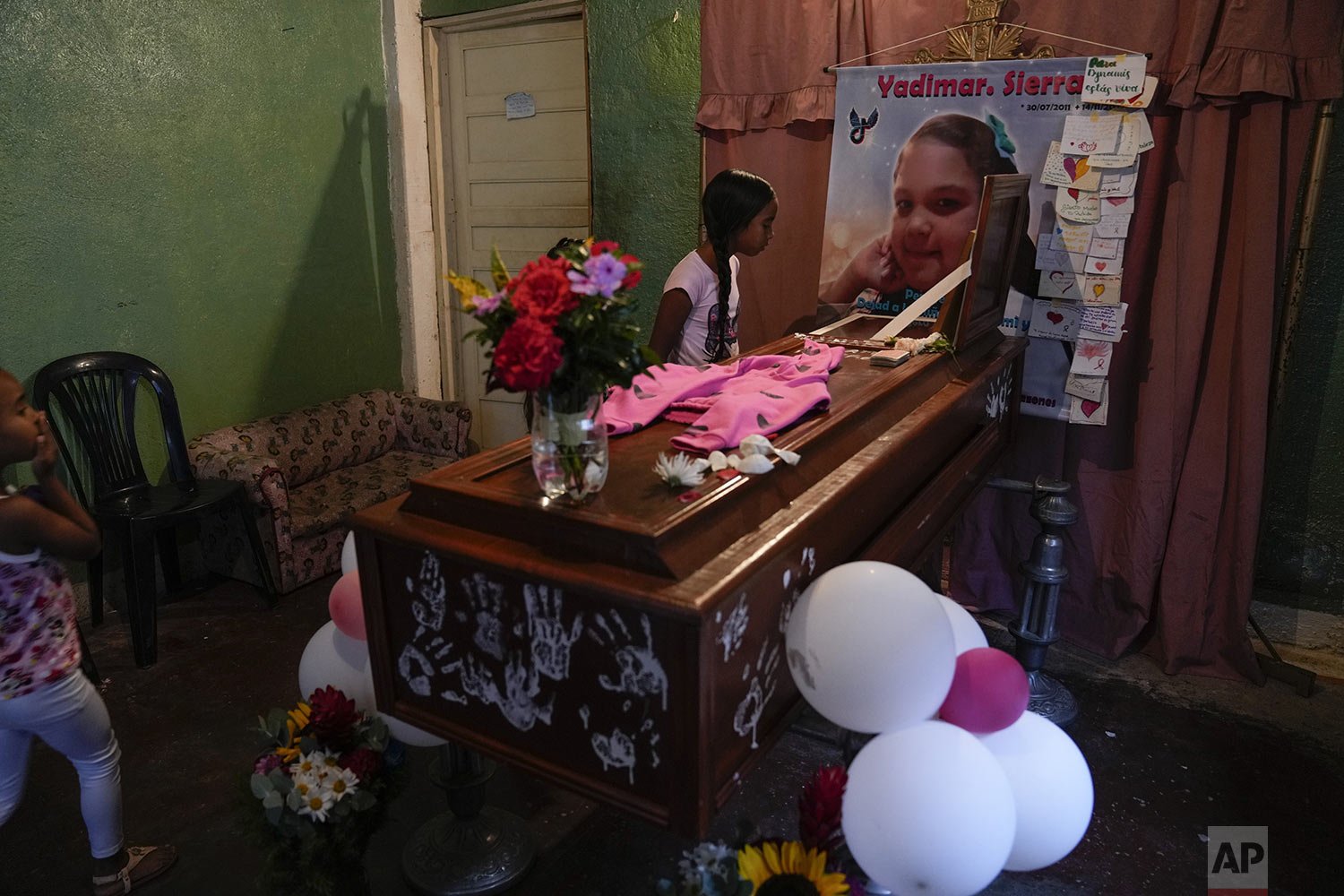  A girl looks into the open casket of Yadimar Sierra, 11, during her wake inside her home in the Petare neighborhood of Caracas, Venezuela, Sunday, Nov. 20, 2022. (AP Photo/Ariana Cubillos) 