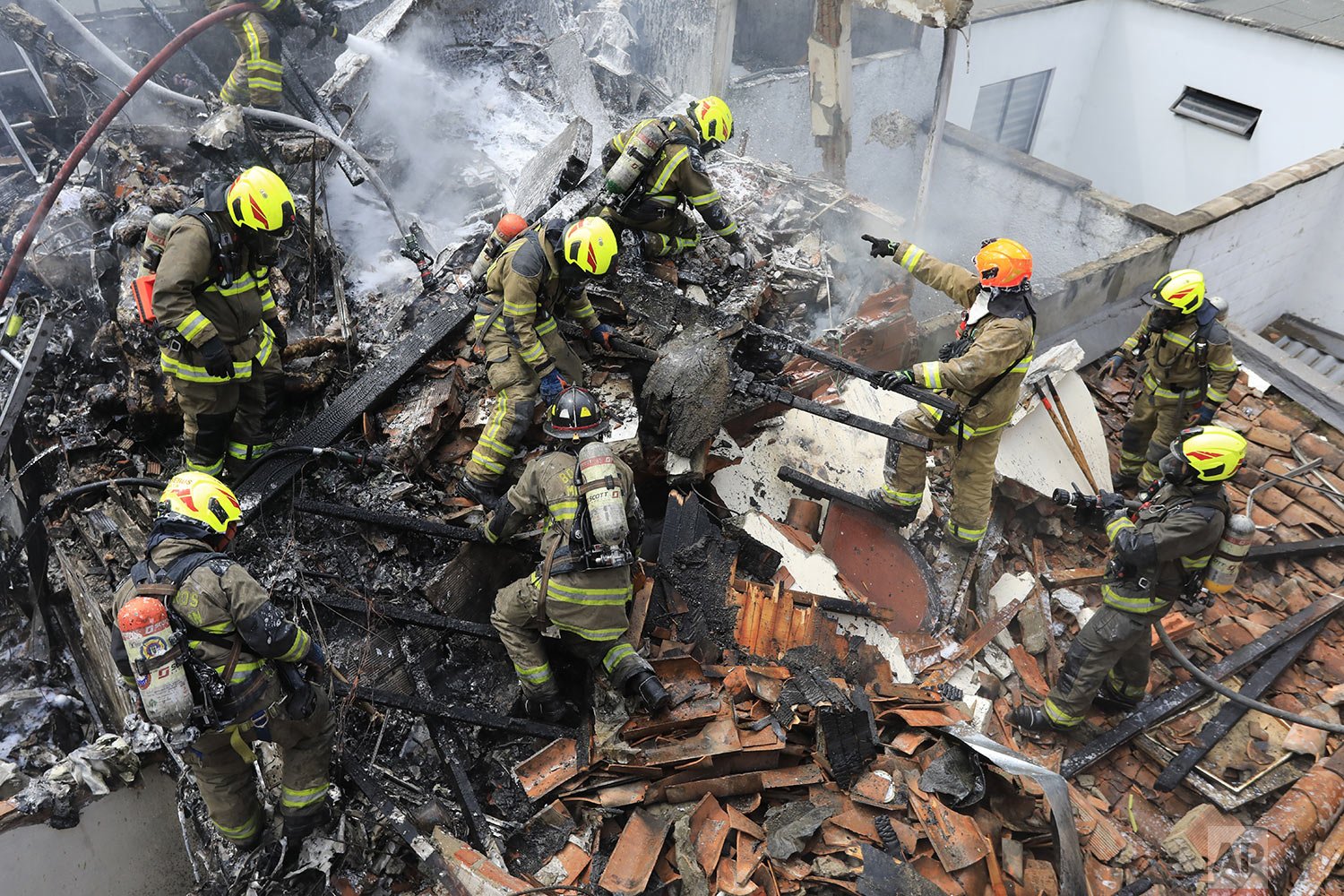  Firefighters work at the crash site of a small plane that fell on top of homes in a residential area of Medellin, Colombia, Monday, Nov. 21, 2022. (AP Photo/Jaime Saldarriaga) 