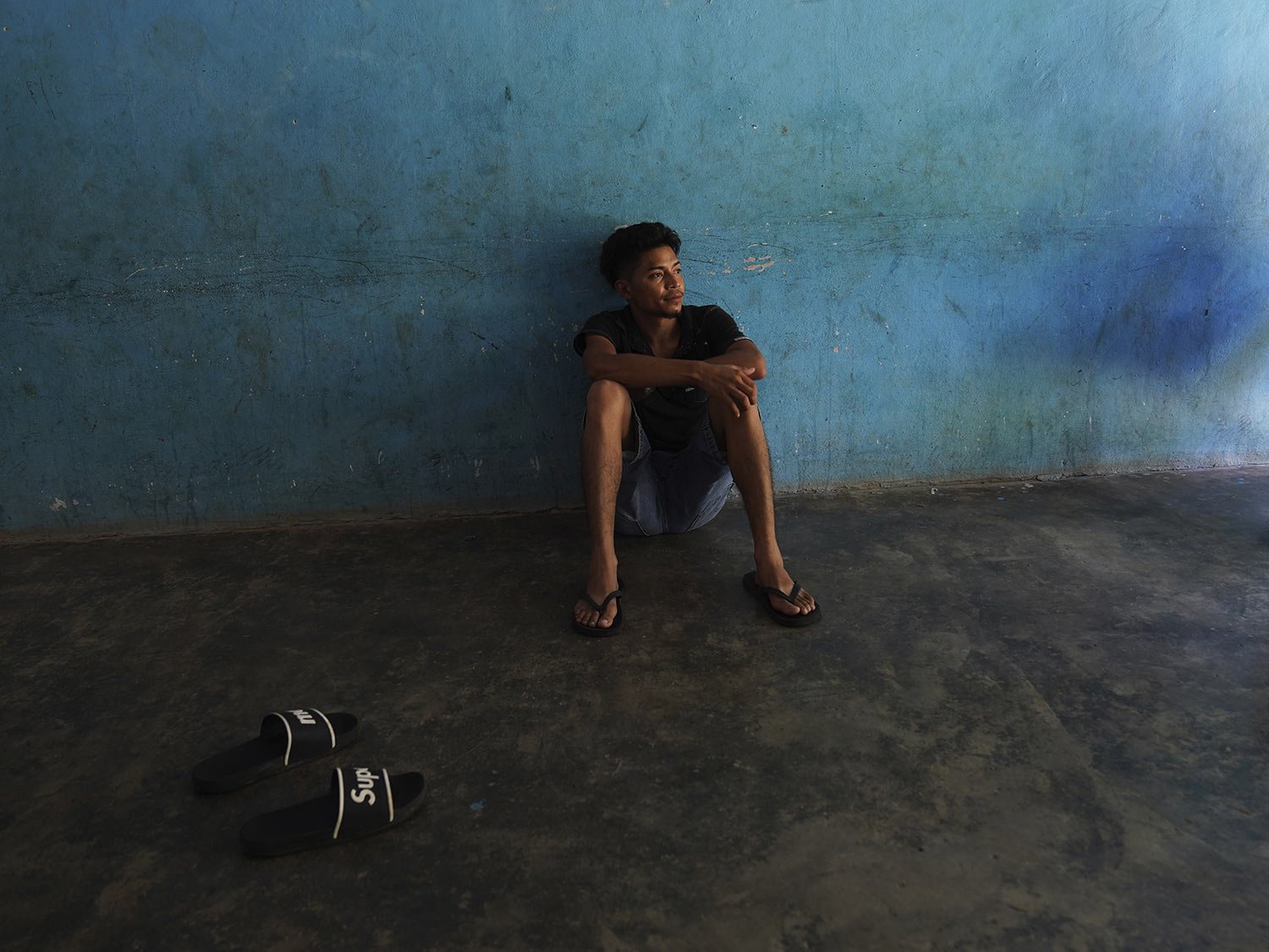  A migrant sits on the floor of a local's home where he is paying to stay while waiting on the Mexican immigration office to accept his application for legal migration documents and give a him "safe passage" permit in Tapachula, Chiapas state, Mexico