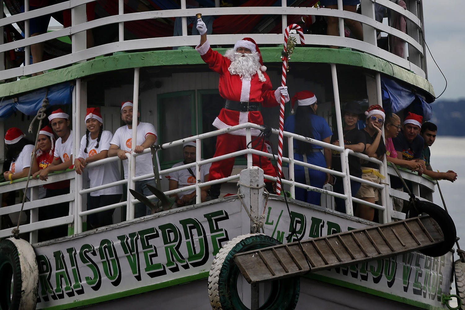  Jorge Barroso, dressed as Santa Claus, rings his bell while standing on the stern of boat as he arrives to distribute gifts to children in the riverside communities of Manaus, Amazonas state, Brazil, Saturday, Dec. 17, 2022. (AP Photo/Edmar Barros) 