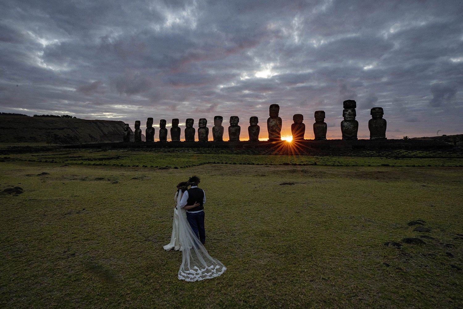  Chilean newlyweds Daniela Figueroa and Ricardo Torres, from Puerto Montt, Chile, look at moai statues at sunrise as they get cell phone photos taken by their tour guide on Ahu Tongariki, Rapa Nui, or Easter Island, Chile, Tuesday, Nov. 22, 2022. (AP