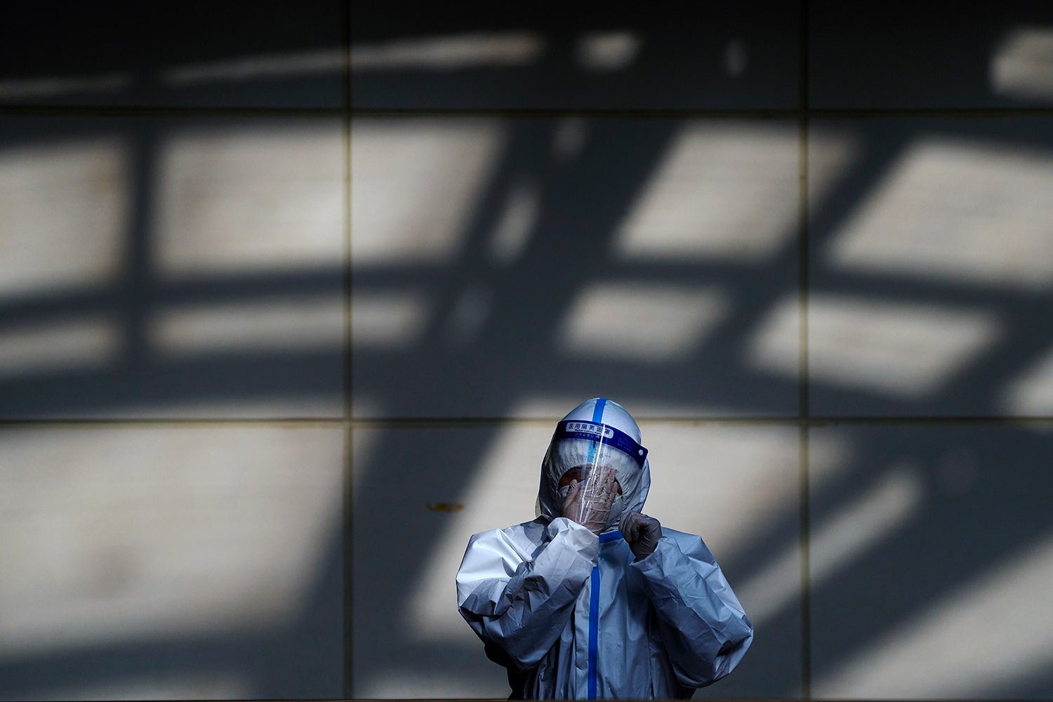  A worker in a protective suit wipes his face shield at a coronavirus testing side in Beijing, Monday, Dec. 5, 2022.  (AP Photo/Andy Wong) 