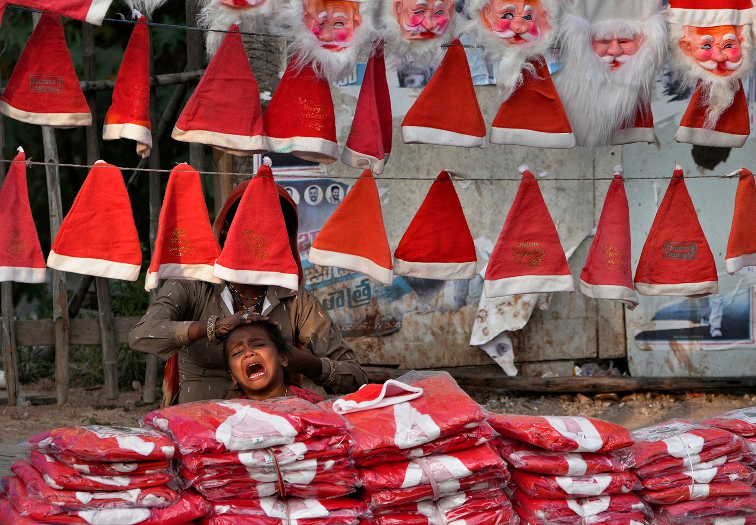  A street vendor selling Santa caps combs her daughter as she waits for buyers ahead of Christmas in Hyderabad, India, Thursday, Dec. 22, 2022. (AP Photo/Mahesh Kumar A.) 