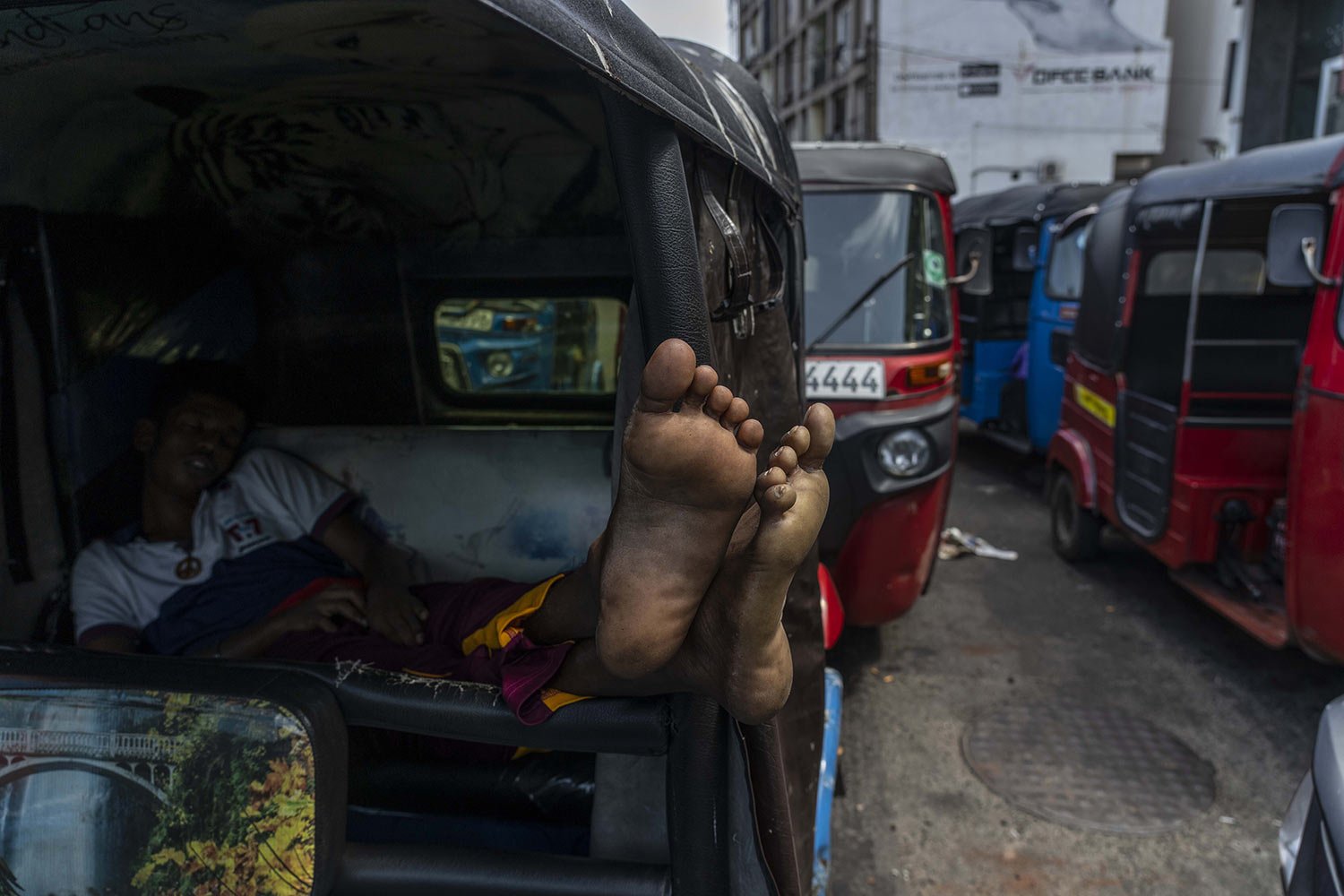  The driver of an auto-rickshaw sleeps inside his vehicle while waiting in line to buy gas at a fuel station in Colombo, Sri Lanka, July 12, 2022. Sri Lanka has been&nbsp;gripped for months by an economic meltdown&nbsp;that has triggered severe short