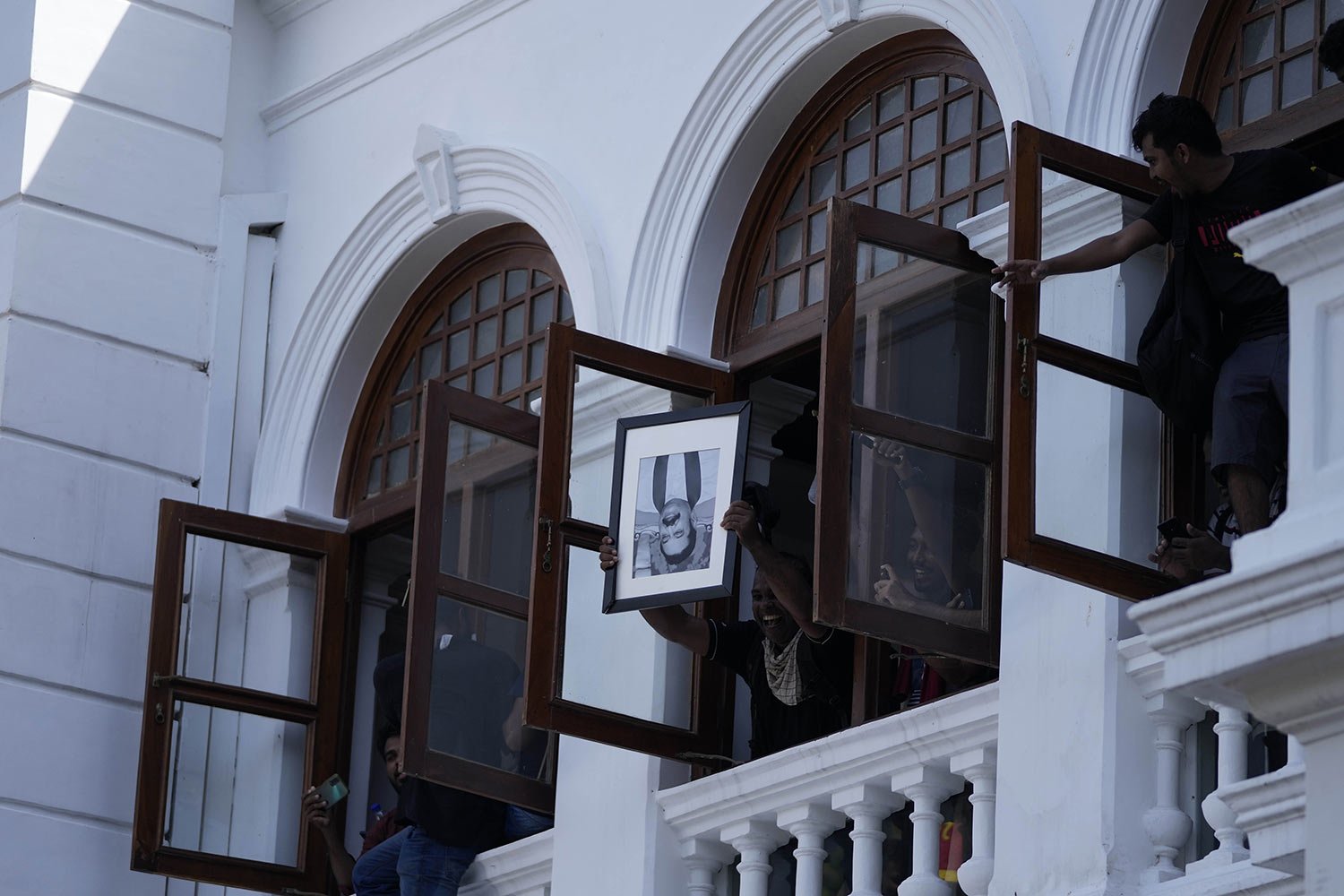  A protester holds a portrait of Sri Lankan Prime Minister Mahinda Rajapaksa upside down after storming the office of President Ranil Wickremesinghe, demanding he resign in Colombo, Sri Lanka, July 13, 2022. (AP Photo/Eranga Jayawardena) 