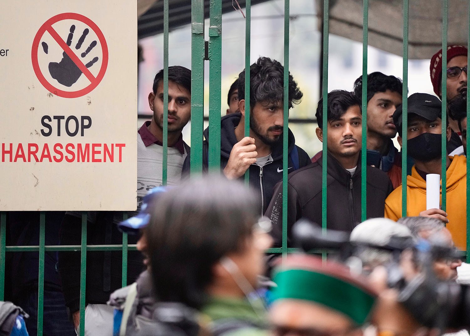  Students watch security personnel guard the main gate of Jamia Millia Islamia university in New Delhi, India, Wednesday, Jan. 25, 2023.  (AP Photo/Manish Swarup) 