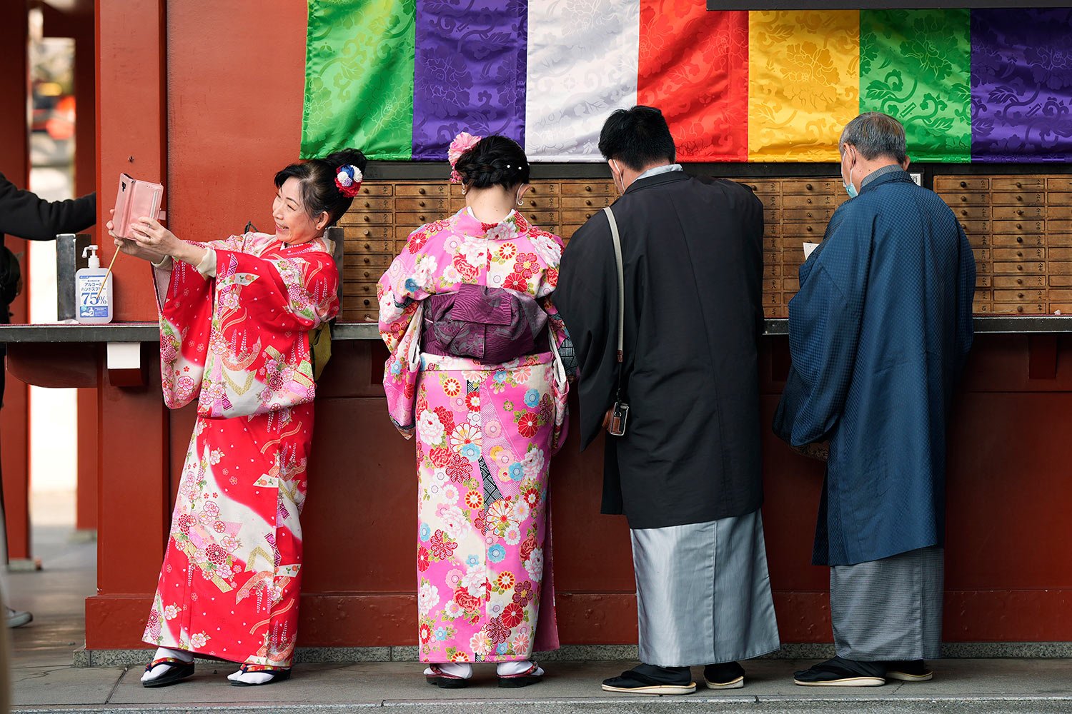  A group of tourists from Singapore wearing traditional Japanese kimonos buy fortune papers as one takes a selfie at Sensoji Buddhist temple in Tokyo, Friday, Jan. 13, 2023. (AP Photo/Hiro Komae) 