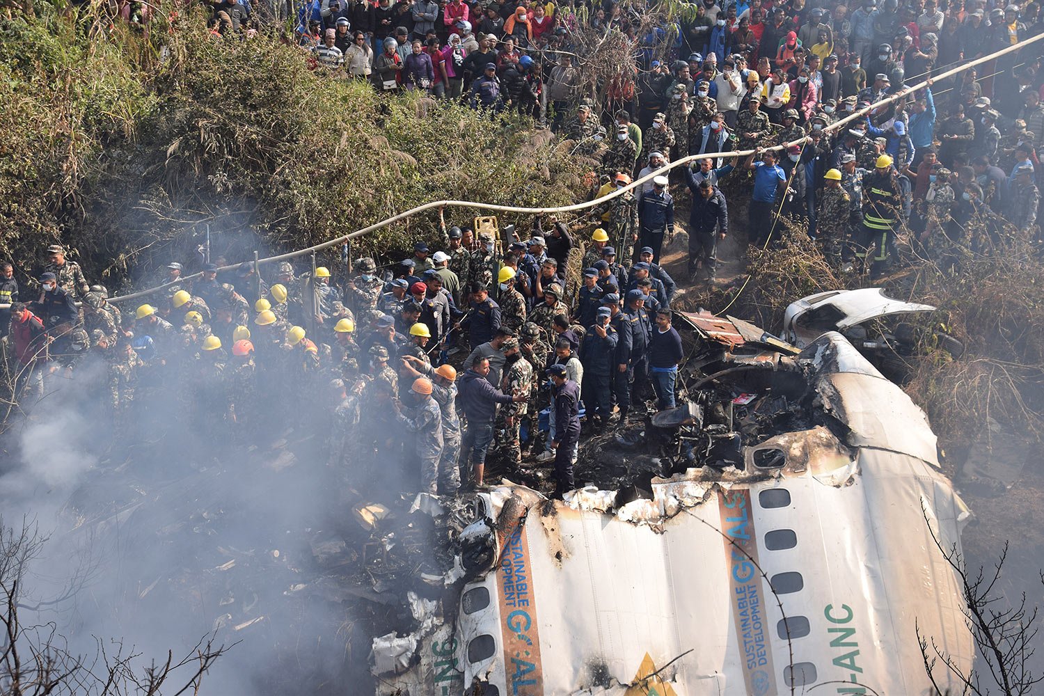  Nepalese rescue workers and civilians gather around the wreckage of a passenger plane that crashed in Pokhara, Nepal, Sunday, Jan. 15, 2023. (AP Photo/Krishna Mani Baral) 