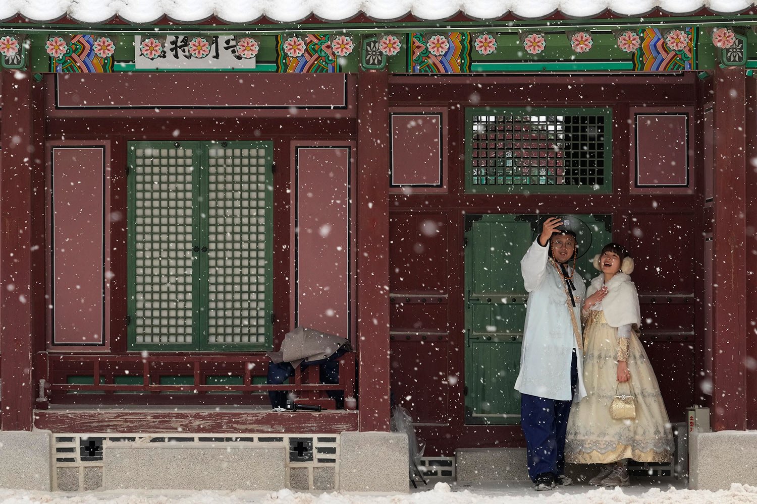 A couple wearing traditional "Hanbok" outfits take a selfie in the snow at the Gyeongbok Palace, the main royal palace during the Joseon Dynasty and one of South Korea's well known landmarks, in Seoul, South Korea, Thursday, Jan. 26, 2023. (AP Photo