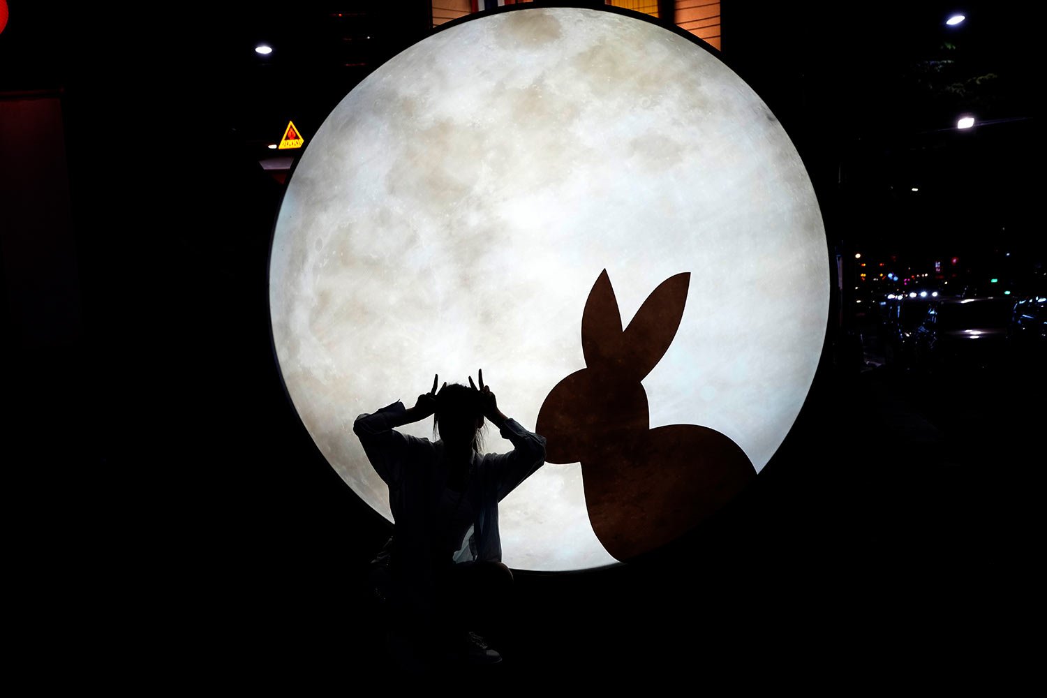 Niu Jiayi, a Chinese tourist, poses for a picture near a light sculpture for the Year of the Rabbit in Bangkok, Thailand, on Jan. 20, 2023.  (AP Photo/Sakchai Lalit) 