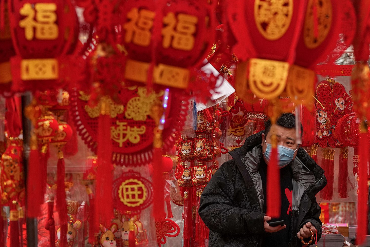  A man wearing a face mask shops for Chinese Lunar New Year decorations at a pavement store in Beijing, Saturday, Jan. 7, 2023. (AP Photo/Andy Wong) 
