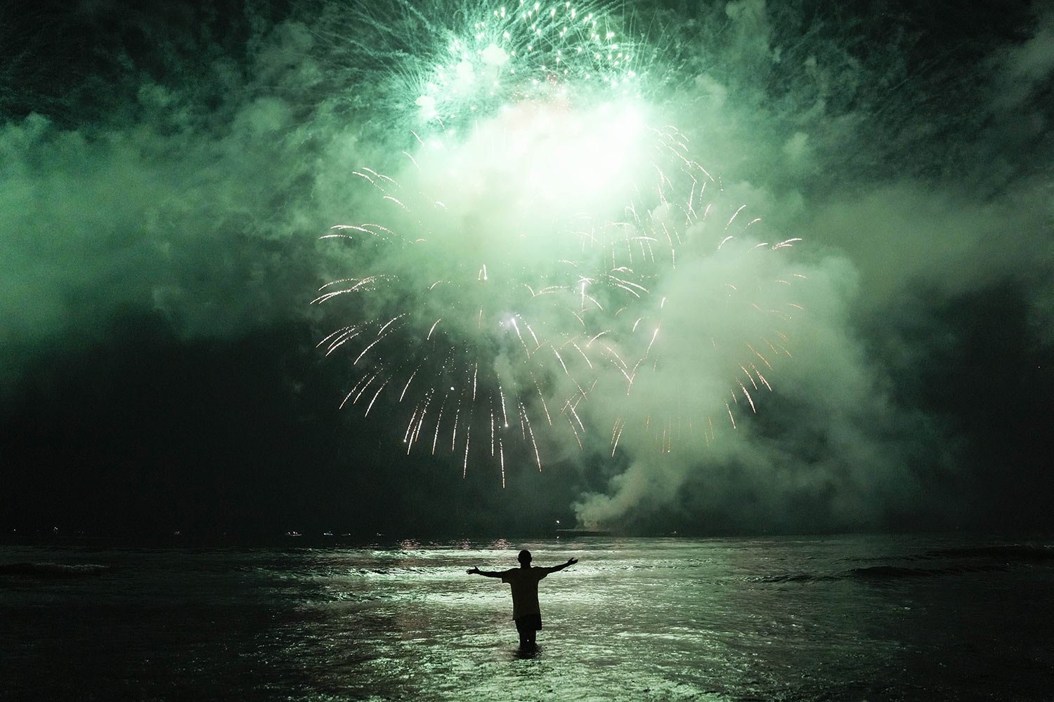  A person watches New Years fireworks explode over the bay in Santos, Brazil, early Jan. 1, 2023. (AP Photo/Matias Delacroix) 