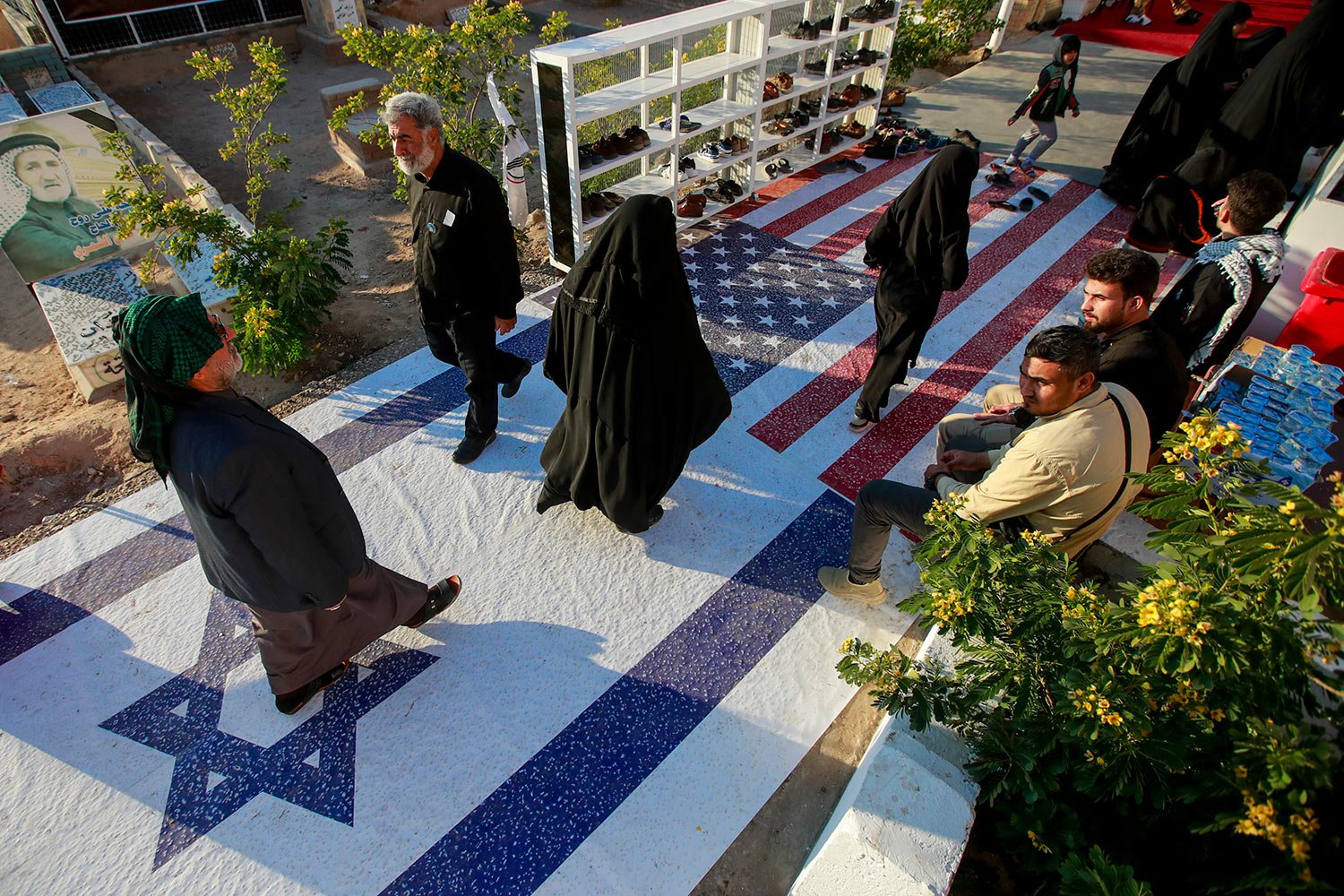 People walk walk over Israeli and American flags during a third anniversary assassination of Abu Mahdi al-Muhandis, deputy commander of Iran-backed militias in Iraq known as the Popular Mobilization Forces and Iran's top general Qassam Soleimani at 