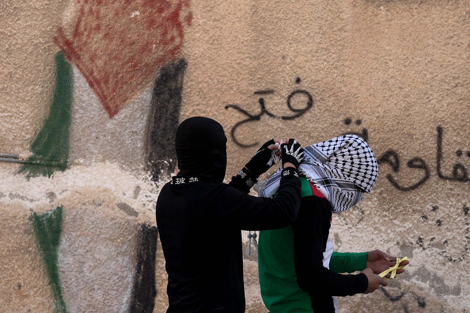  A Palestinian youth assists his friend to tie his scarf before a weekly protest in the West Bank town of Kfar Qaddum, Friday, Jan. 13, 2023. (AP Photo/ Maya Alleruzzo) 