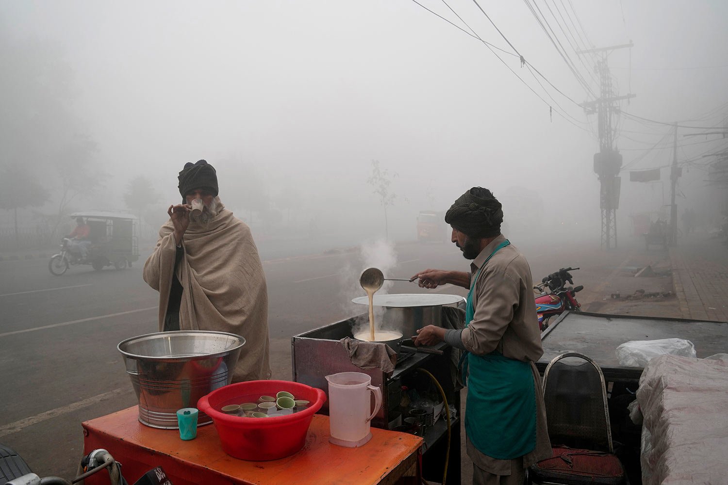  A man drinks tea at a roadside stall as heavy fog reduces visibility in Lahore, Pakistan, Monday, Jan. 2, 2023. (AP Photo/K.M. Chaudary) 