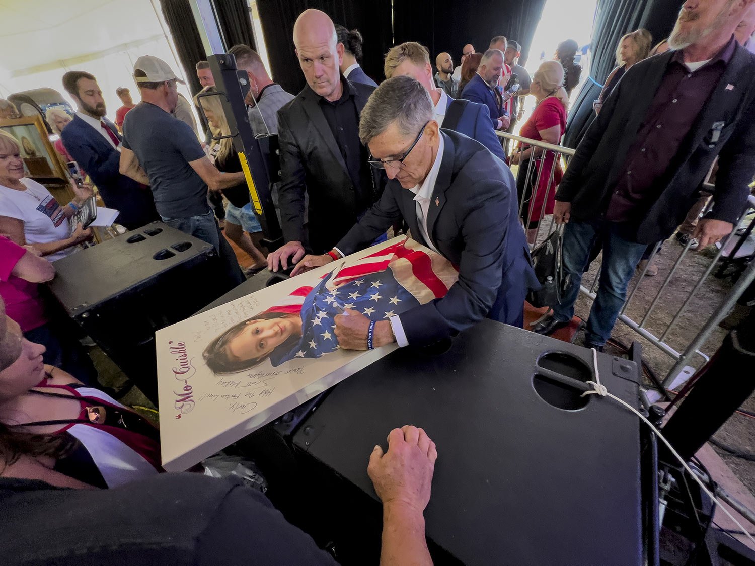  Michael Flynn, a retired three-star general who served as President Donald Trump's national security advisor, autographs a poster of a girl wrapped in an American flag during the ReAwaken America Tour at Cornerstone Church in Batavia, N.Y., Aug. 12,