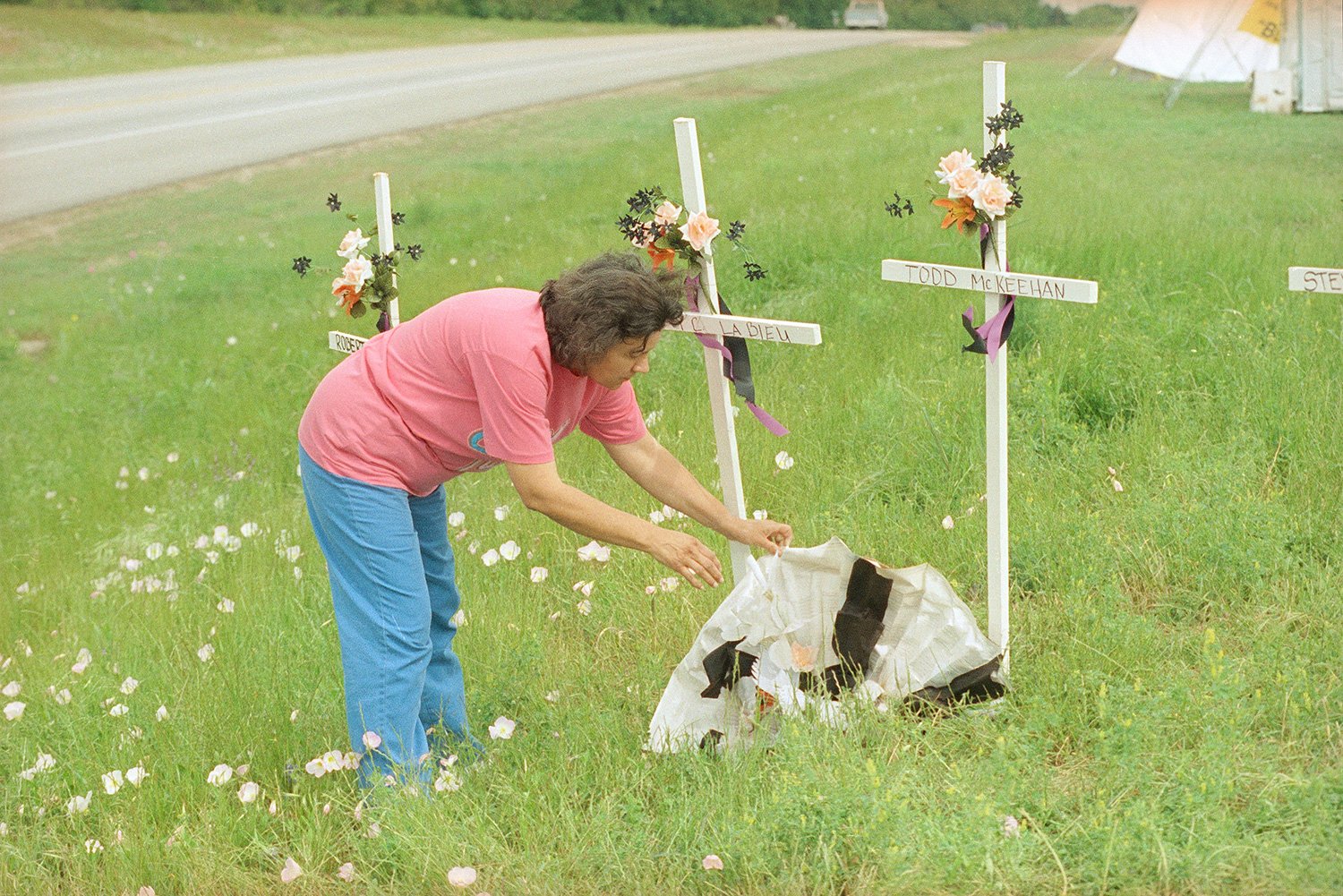  Lidia Castillo tries to straighten a flower arrangement at the crosses on t-shirt hill, near Waco, Texas, May 2, 1993. There are four crosses commemorating the Bureau of Alcohol, Tobacco and Firearms agents killed in a shootout with Branch Davidians