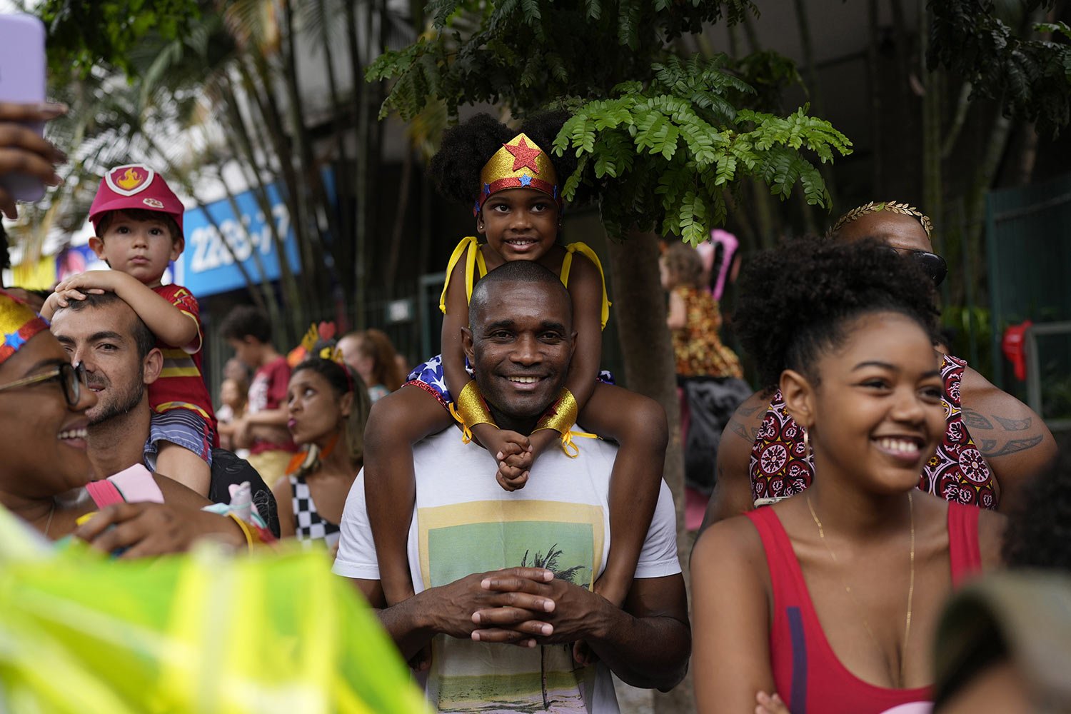  A youth dressed as the fictional heroine Wonder Woman sits on her relative's shoulders as she watches the "Gigantes da Lira" street block party in Rio de Janeiro, Brazil, Sunday, Feb. 12, 2023. Merrymakers took to the streets for open-air block part