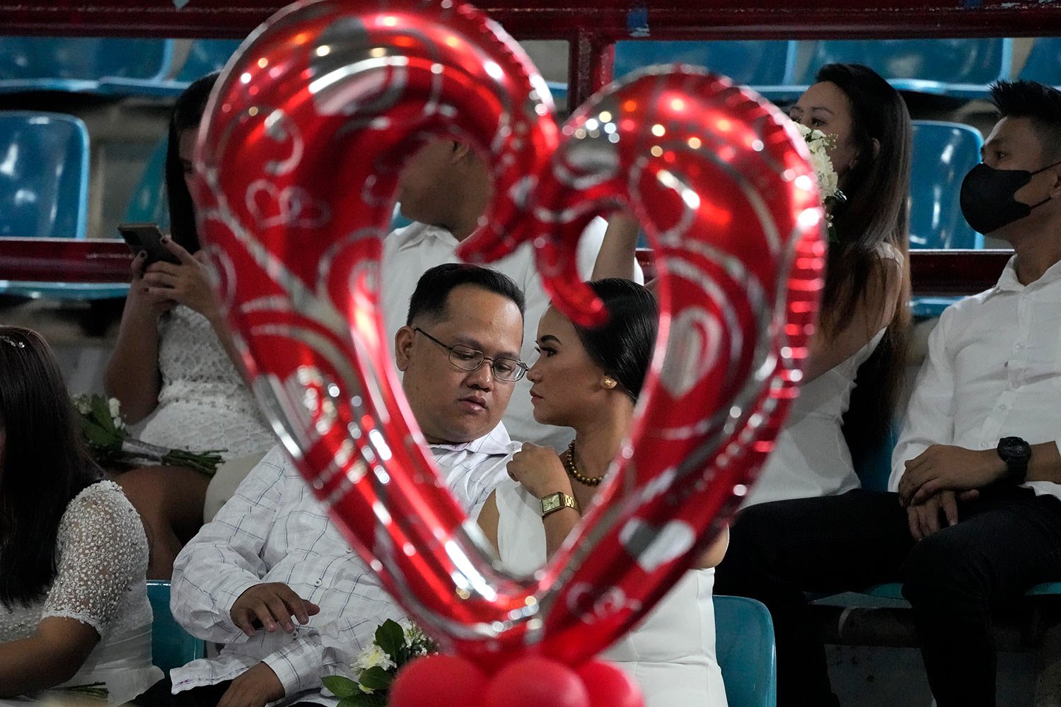  A groom checks his bride's dress as they wait for ceremonies to begin at a mass wedding in San Juan city, Manila, Philippines to celebrate Valentines day Tuesday, Feb. 14, 2023.  (AP Photo/Aaron Favila) 