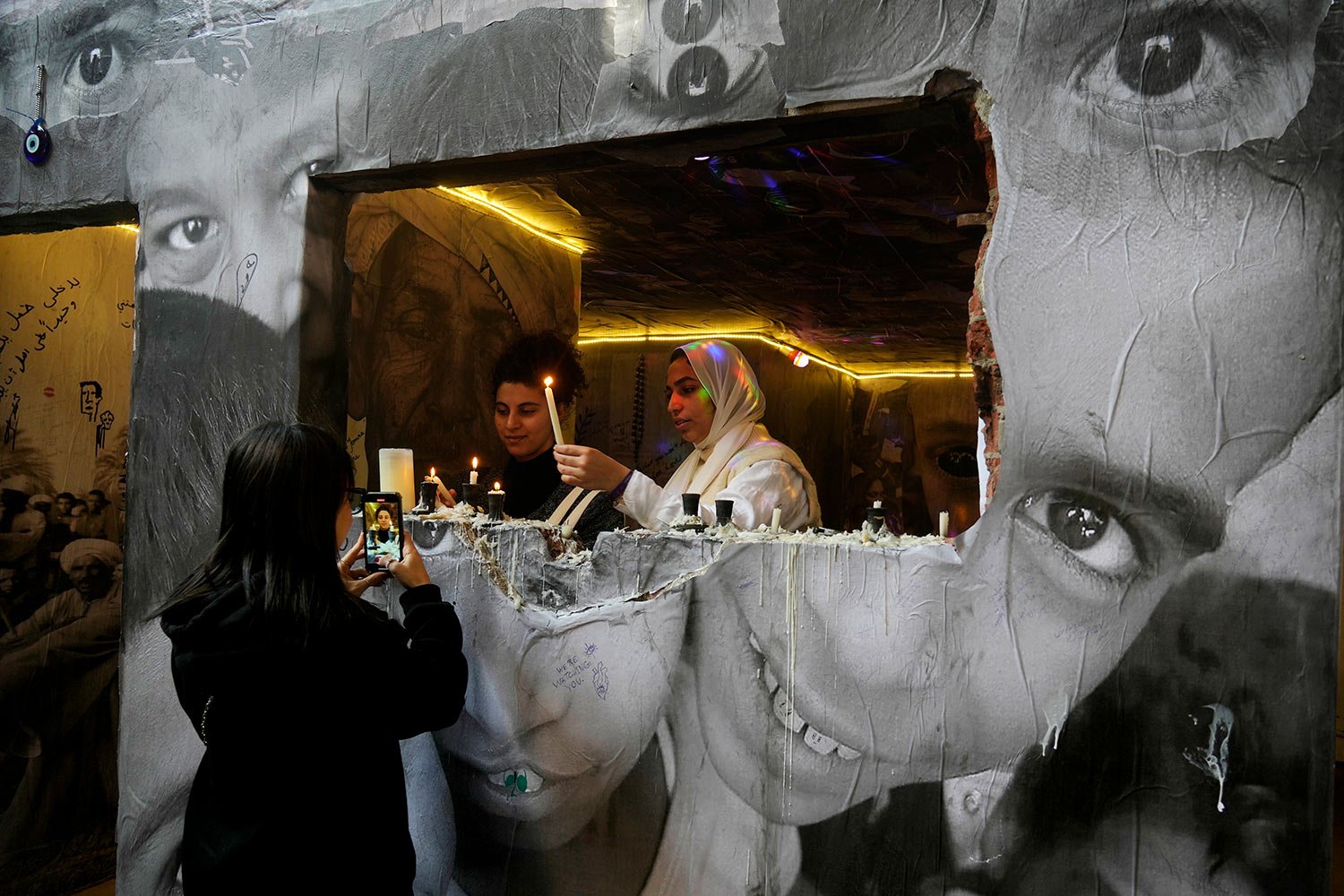  Visitors light candles at the art work "Communications" of Egyptian artist Mahmoud Hawary in downtown Cairo, Egypt, Saturday, Feb. 18, 2023. (AP Photo/Amr Nabil) 